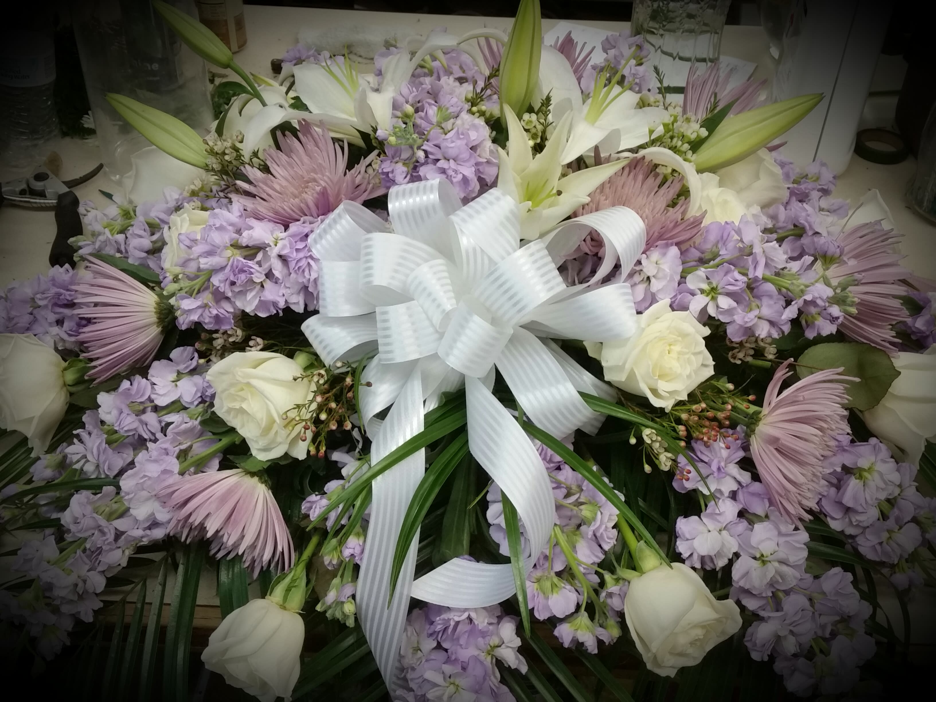 Lavender and white floral arrangement with a large white ribbon bow