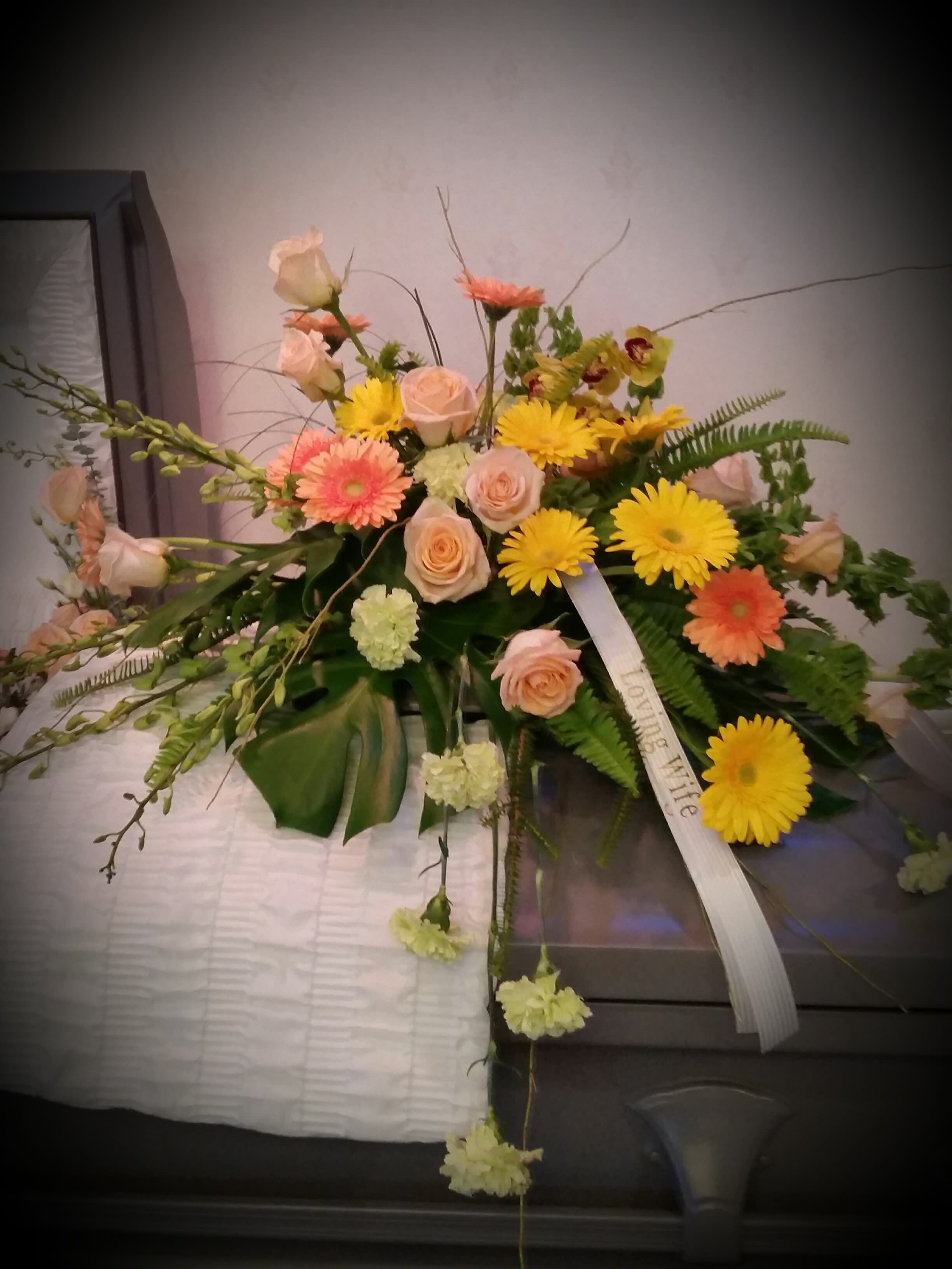 Mixed floral spray with roses and daisies on a casket