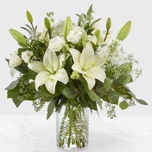 White lilies and roses arranged in a clear glass vase