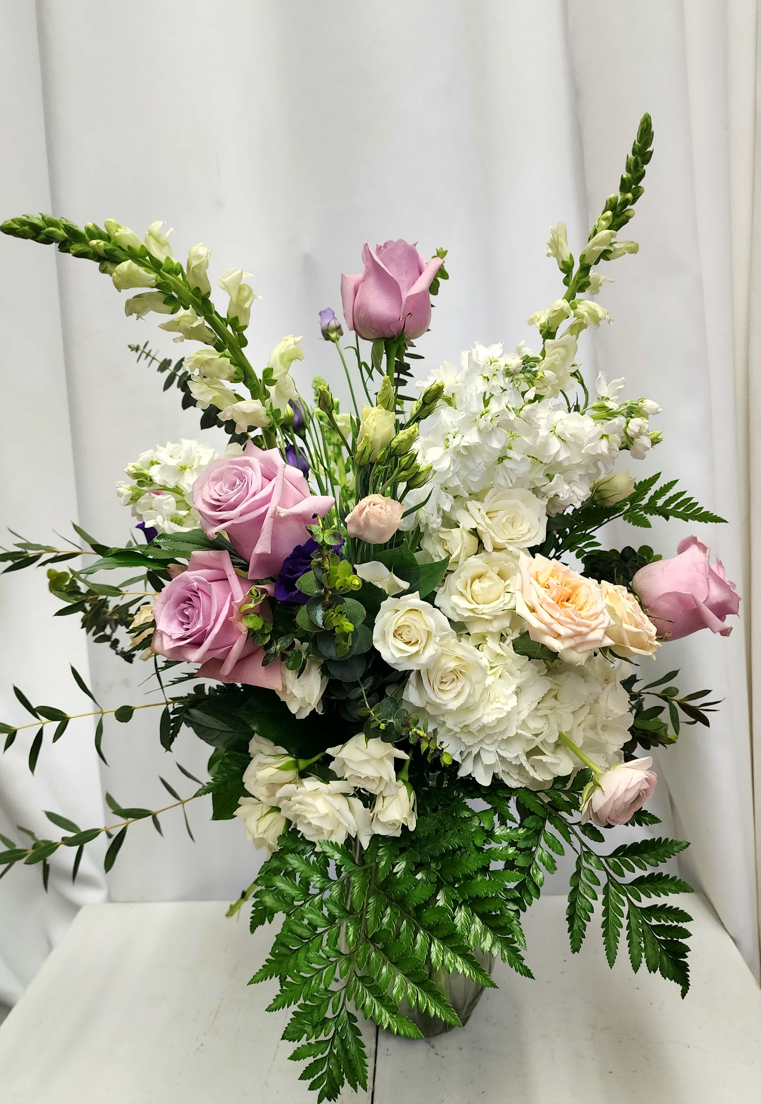 Pink and white roses with white blooms in a vase arrangement