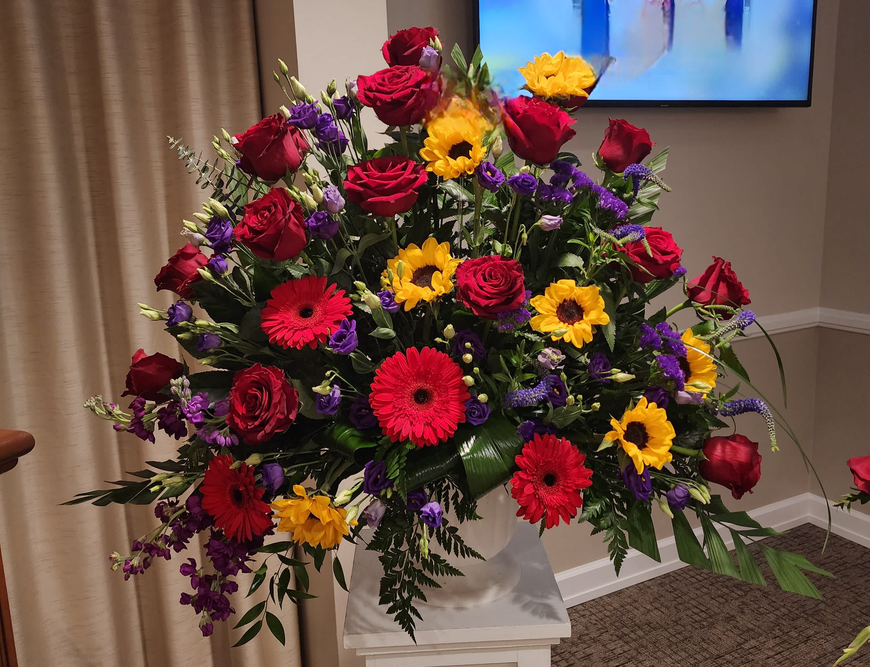 Heather's Haven Pedestal - A stunning display of Red Roses, Yellow sunflowers, Red Gerbera Daisies, Purple Lisianthus and Veronica create this beautiful display of love and admiration. 