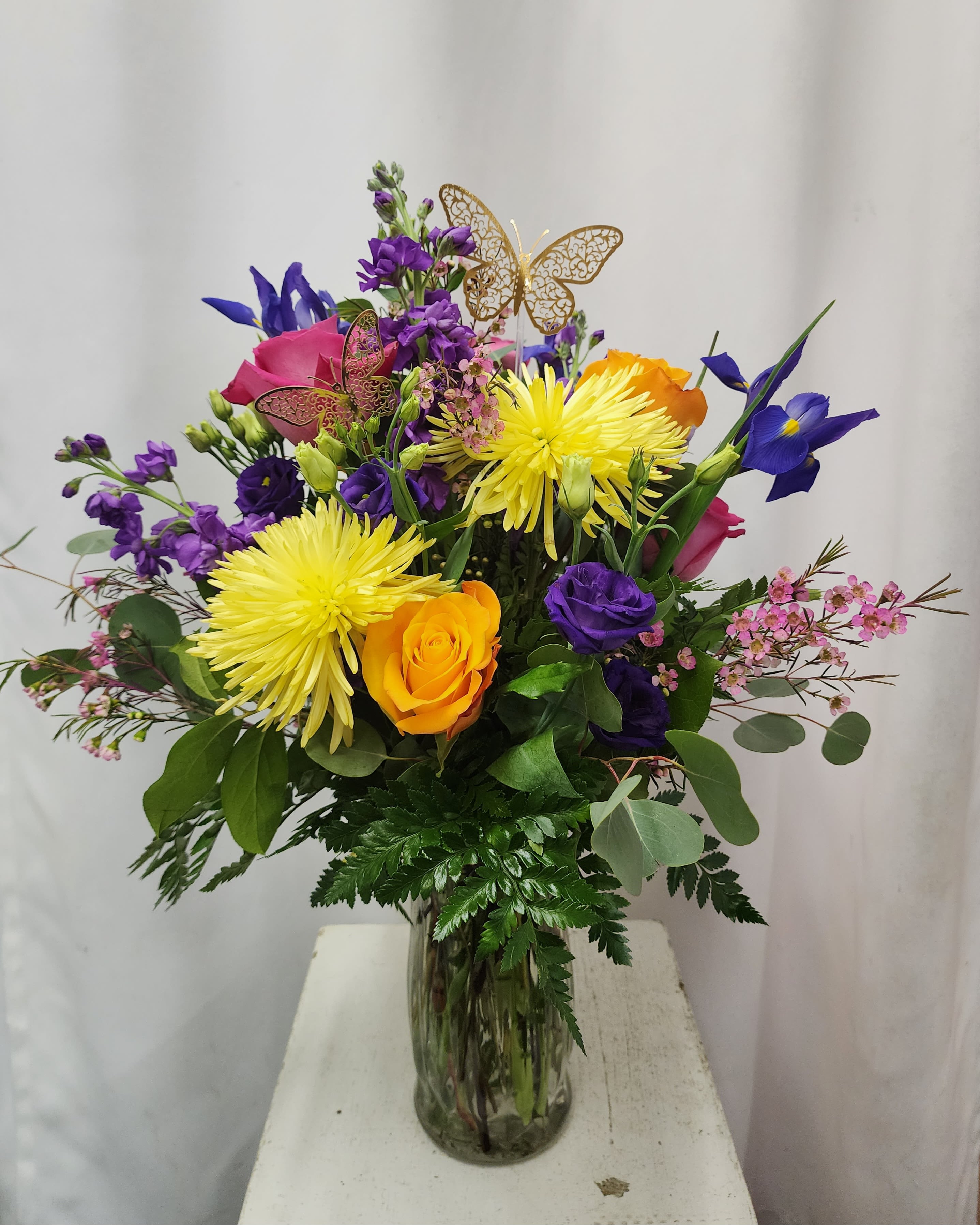 Mixed bouquet in a glass vase with yellow, purple, pink, and orange flowers