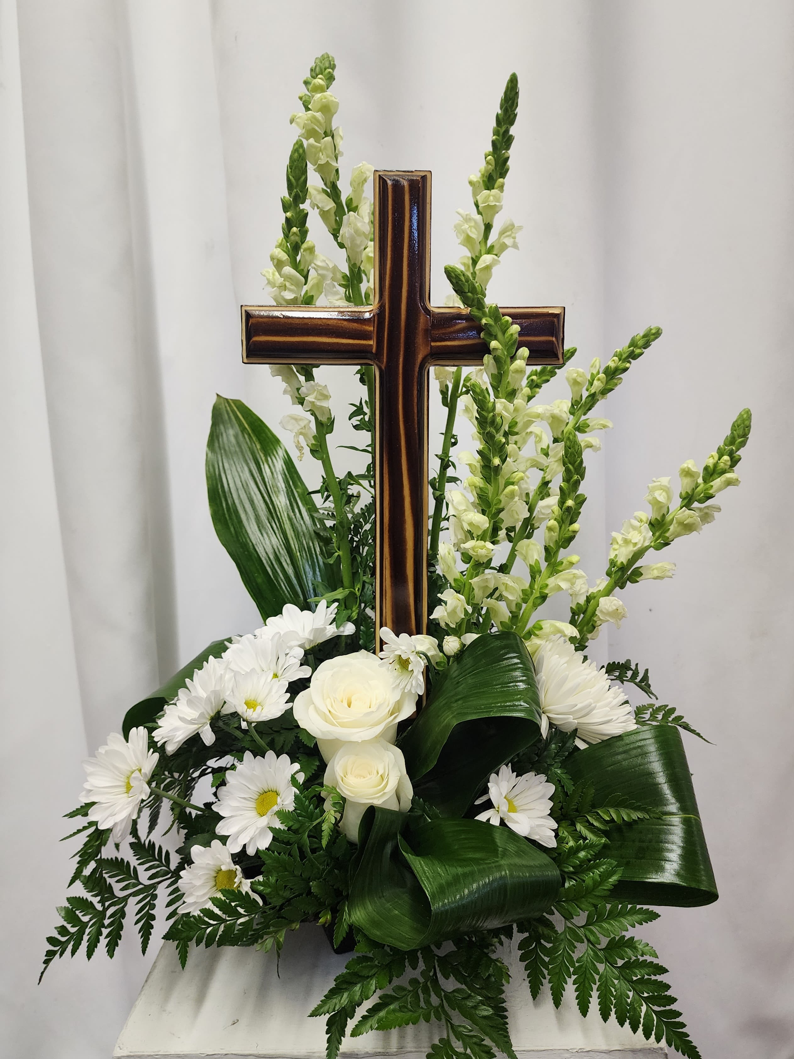 White floral arrangement with a wooden cross centerpiece