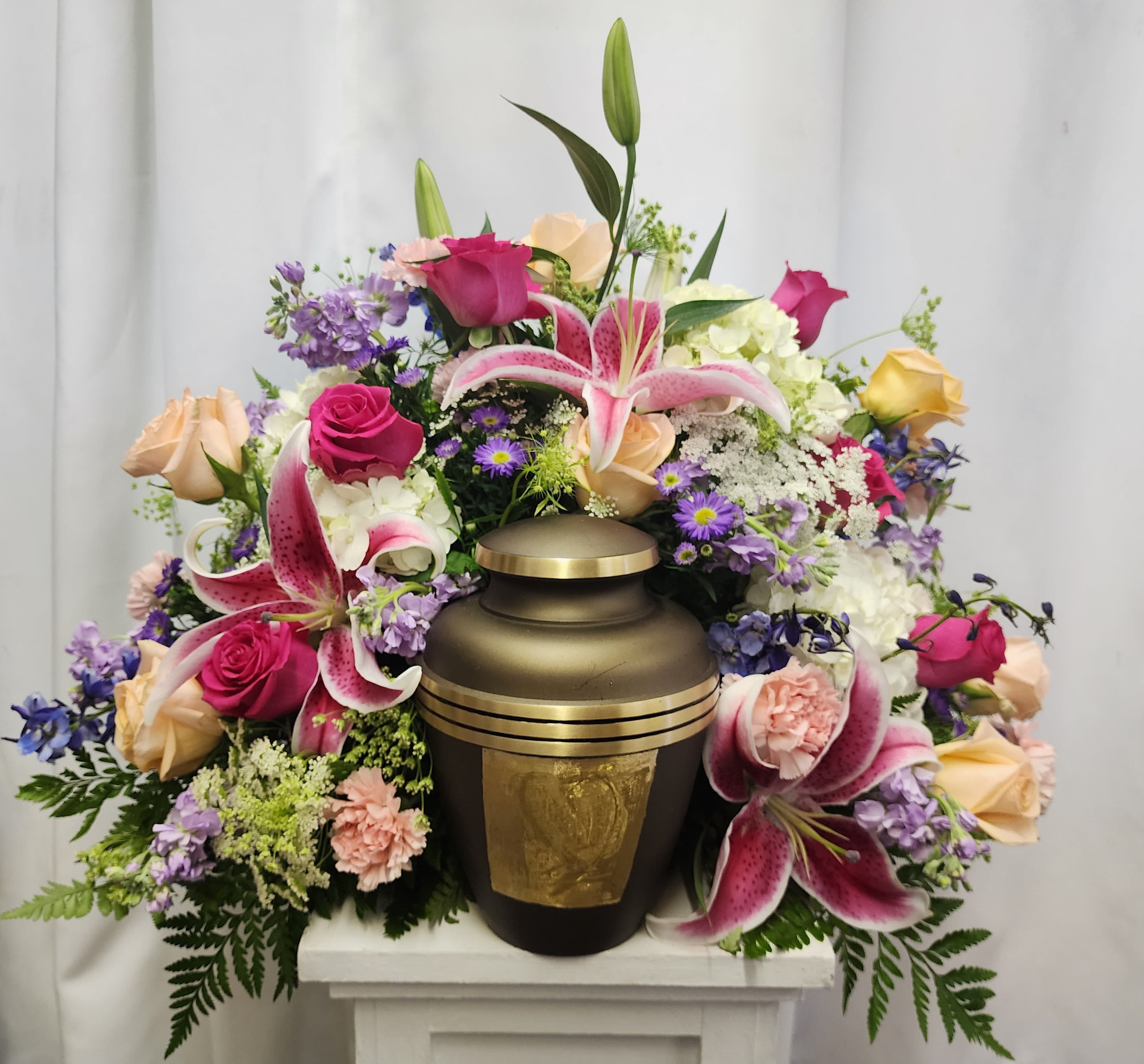 Floral arrangement surrounding a bronze urn with pink lilies and roses