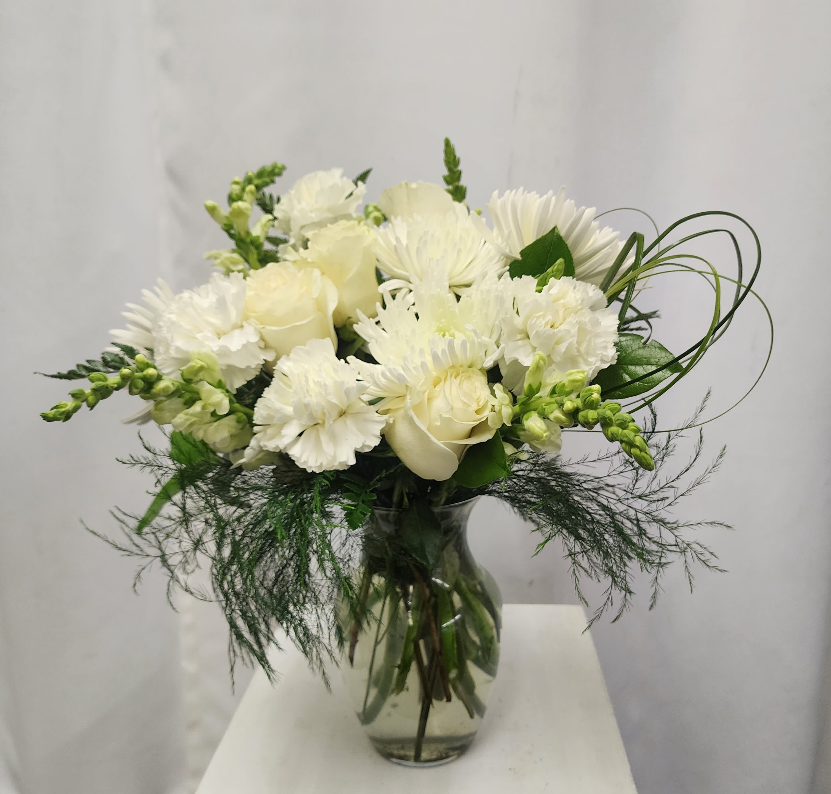 White bouquet of roses, chrysanthemums, and carnations in a glass vase