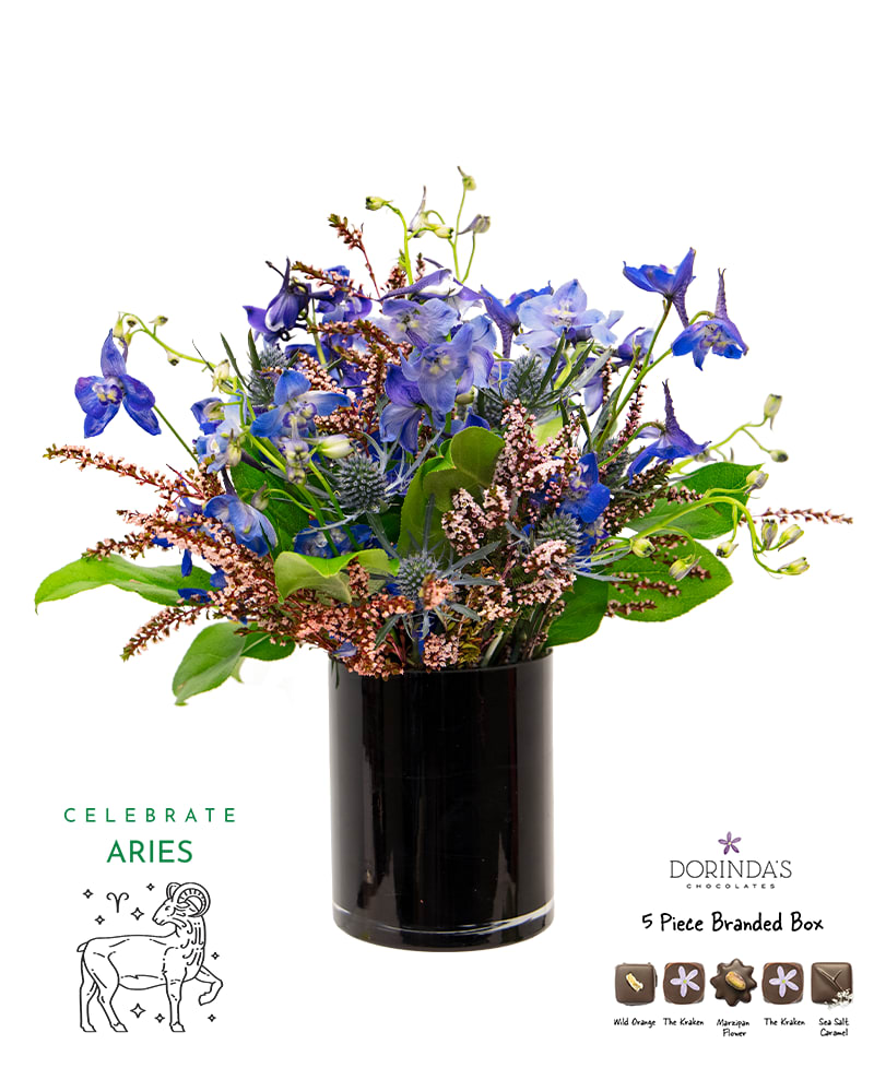 Blue floral arrangement in a black vase with a chocolate box and Aries graphic