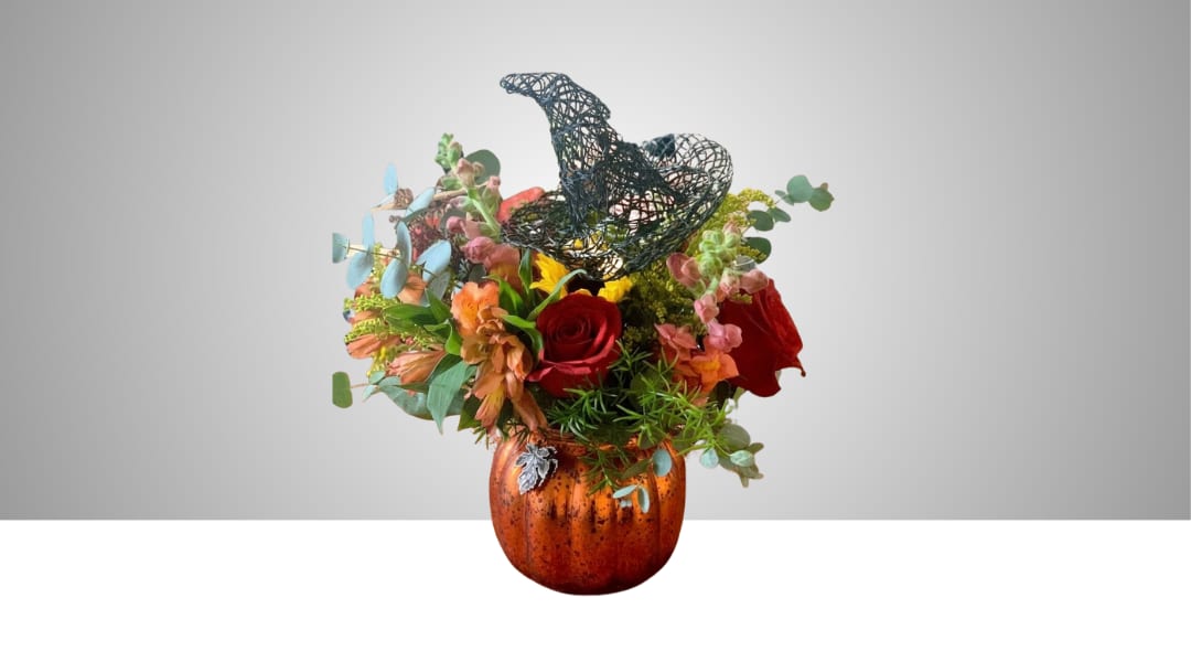 Mixed bouquet in an orange pumpkin vase with a black witch hat topper