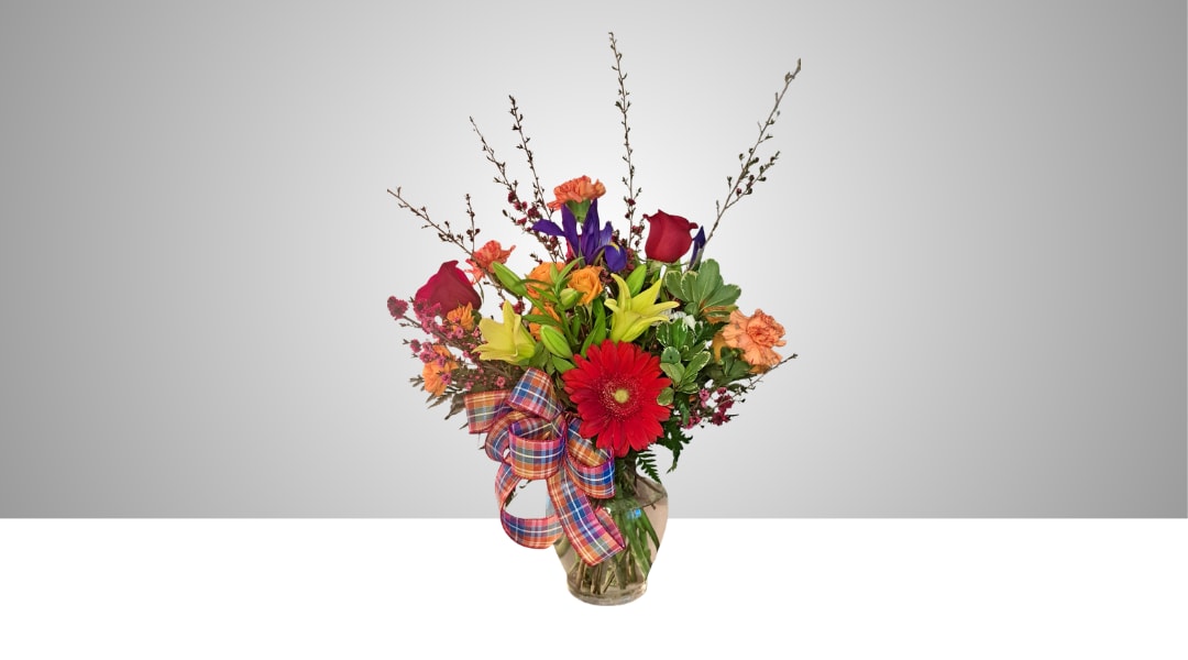 Mixed bouquet with roses, lilies, gerbera daisies, and carnations in a glass vase