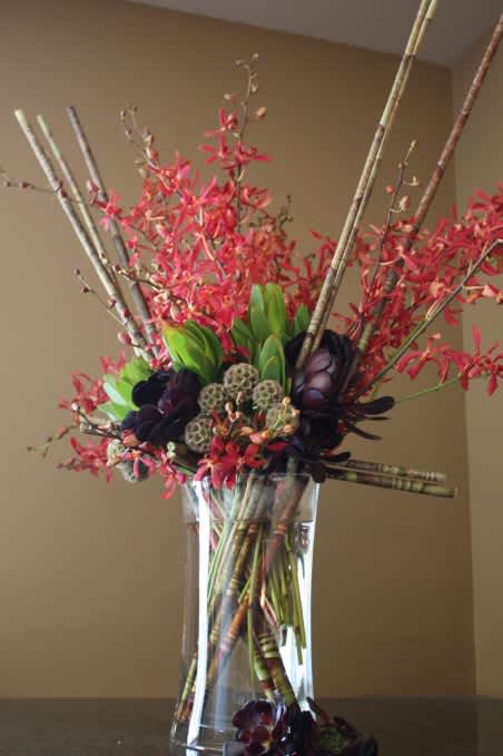 Tall floral arrangement with red blooms in a clear glass vase