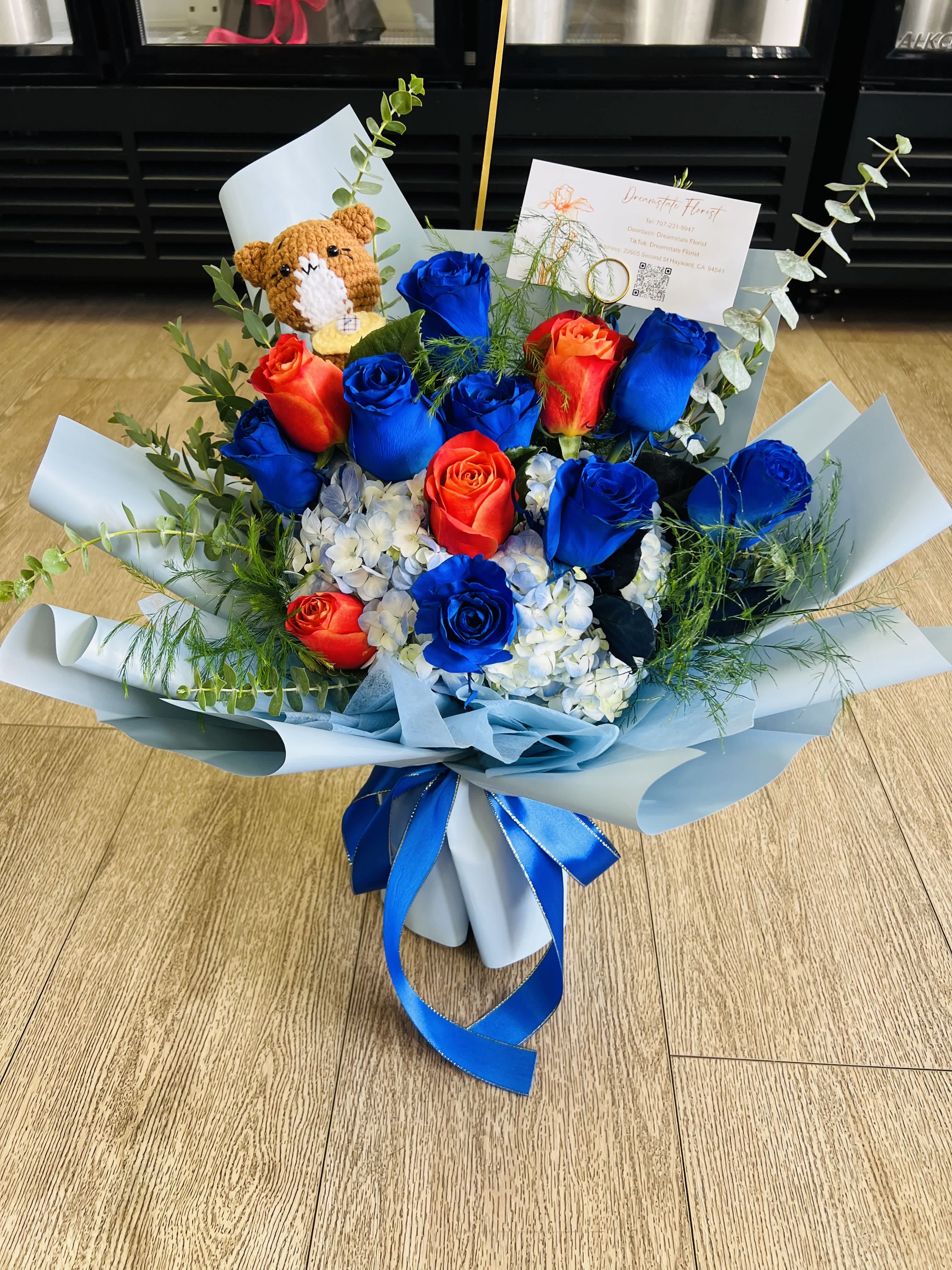 Bouquet of blue and red roses with a small teddy bear and ribbon wrap