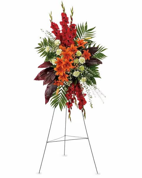 Tall standing floral spray with red and orange flowers on an easel