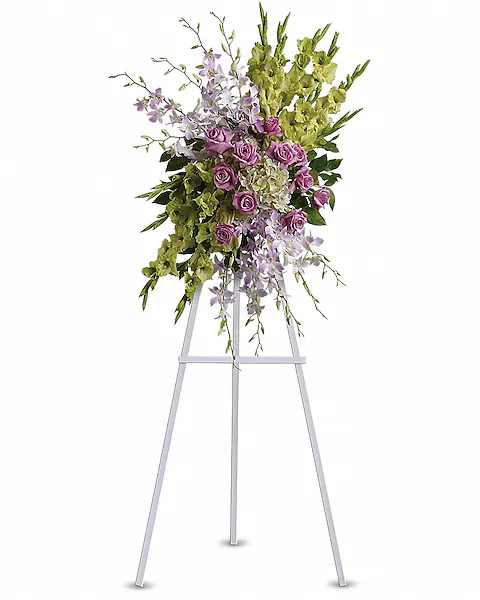 Tall floral spray with purple roses and green orchids on a metal easel
