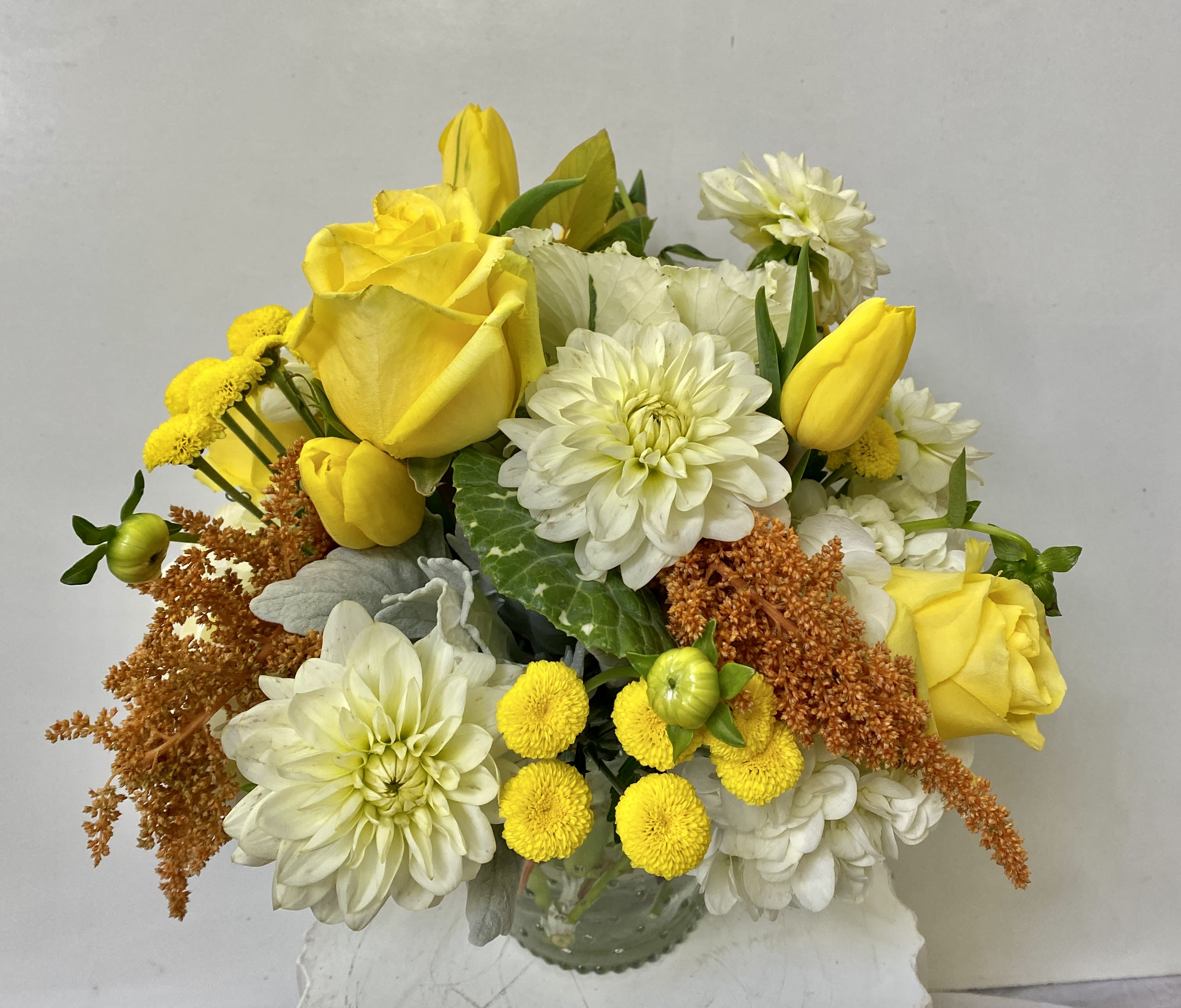 Yellow roses and white dahlias in a glass vase