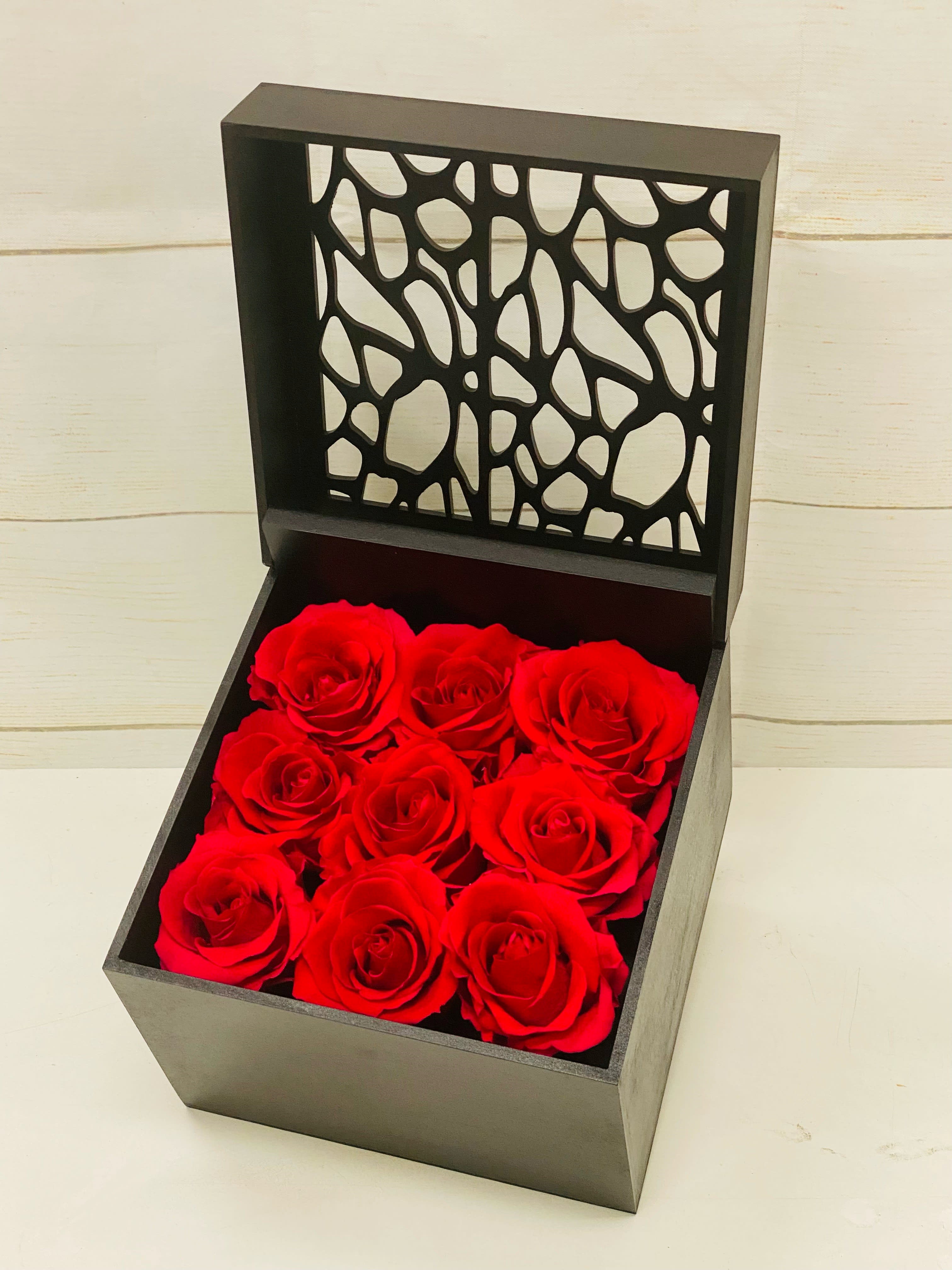 Square black gift box of nine red roses with an open decorative lid