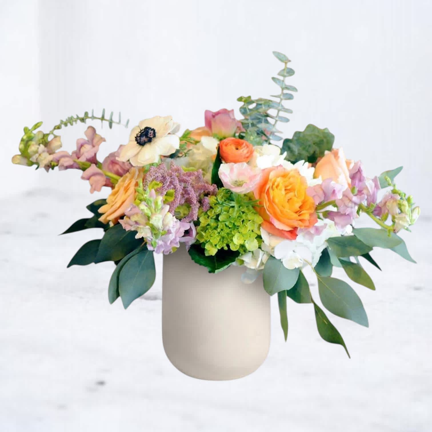 Mixed pastel flower arrangement in a beige vase