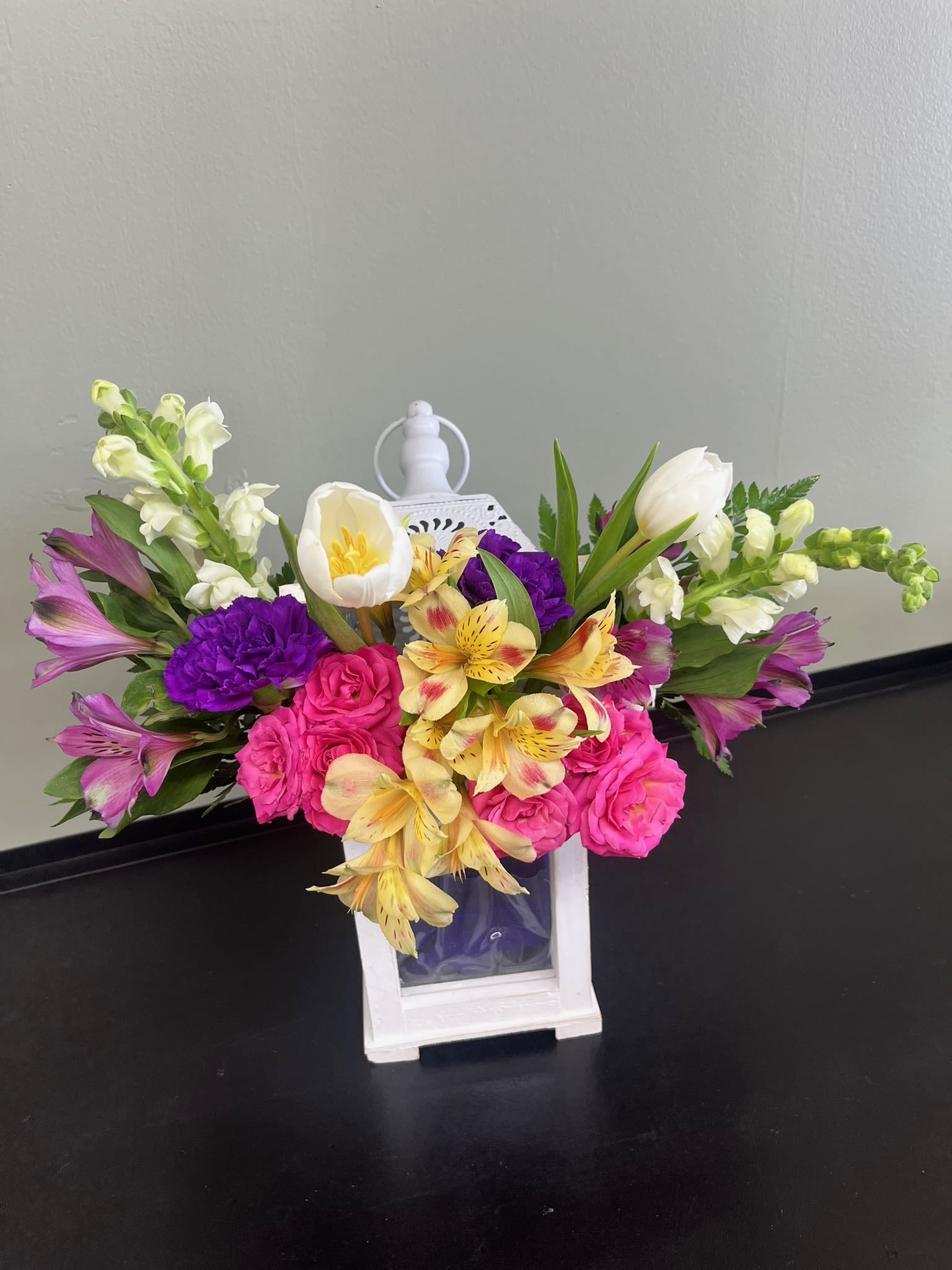 Colorful bouquet in a white lantern vase with pink, purple, yellow, and white flowers