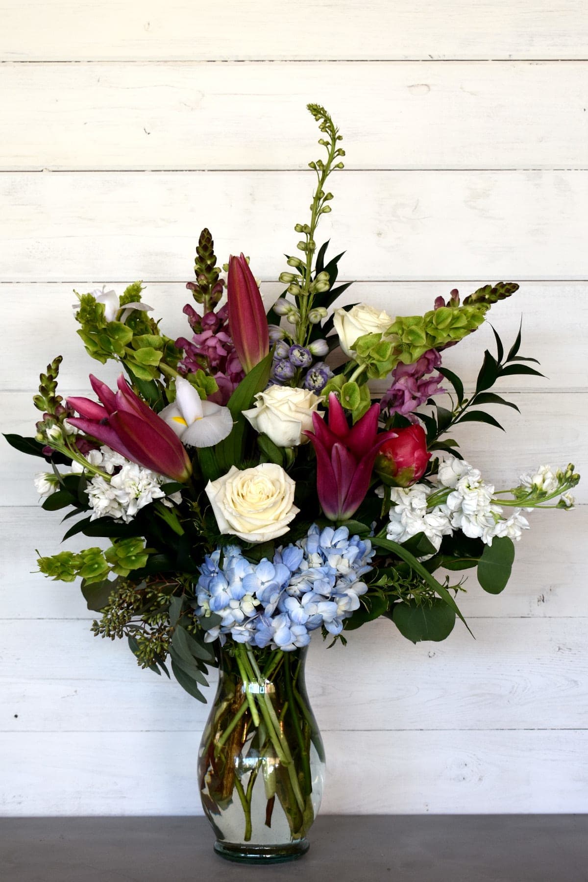 Mixed bouquet in a glass vase with pink lilies, white roses, and blue hydrangeas
