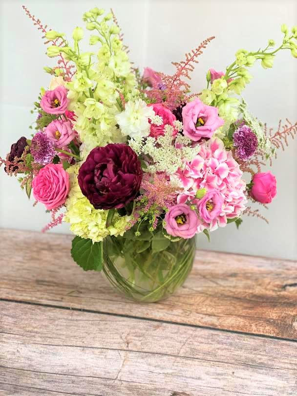 Pink and burgundy flowers arranged in a glass vase