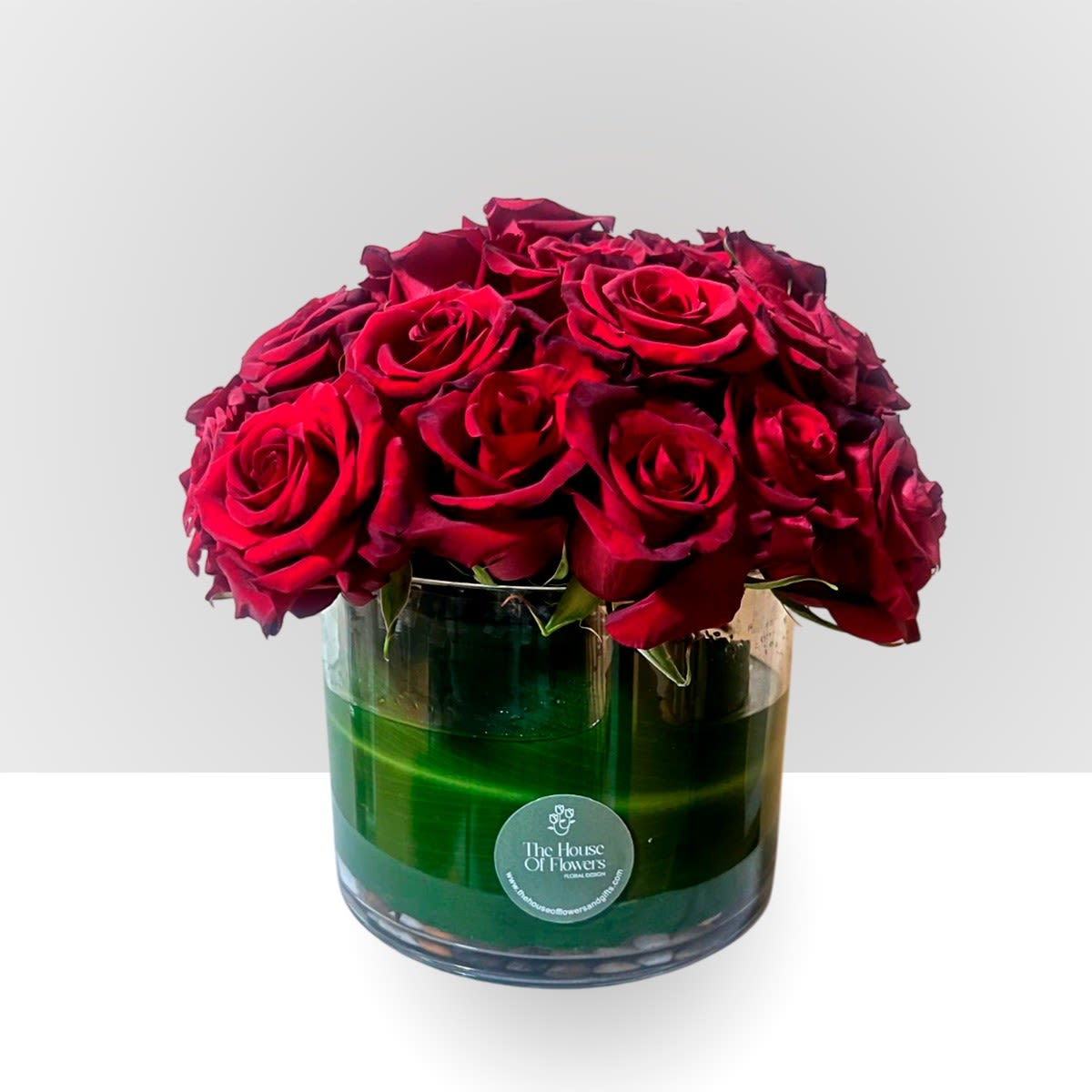 Red roses arranged in a clear glass vase with green water