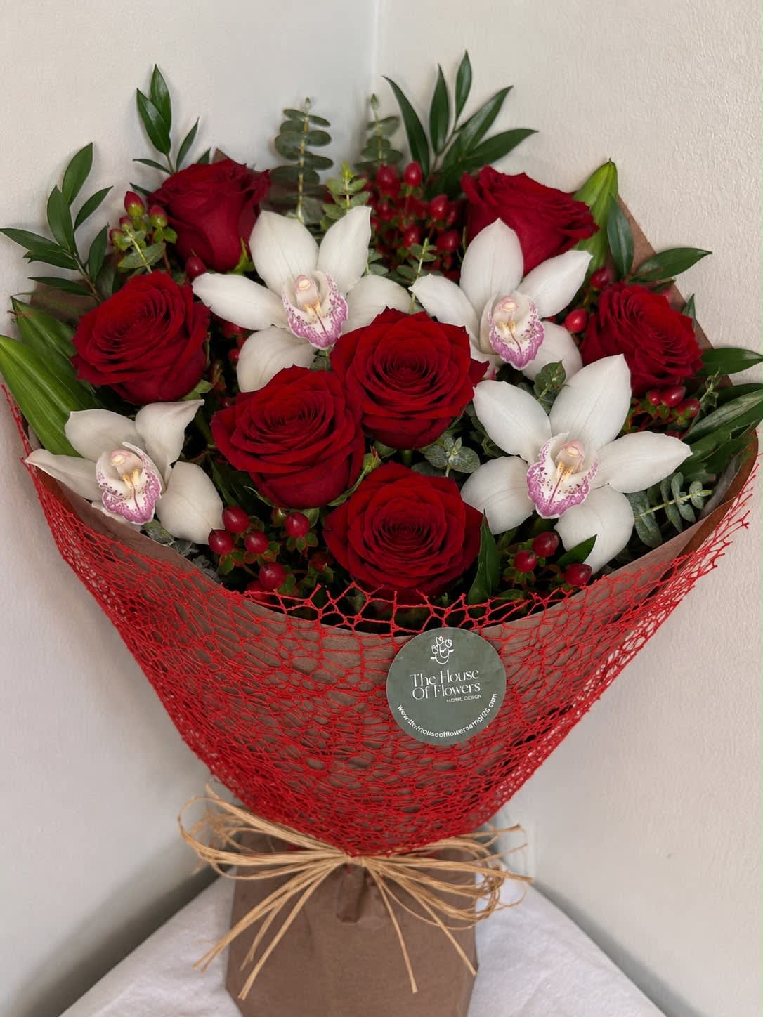 Bouquet of red roses and white orchids wrapped in red mesh