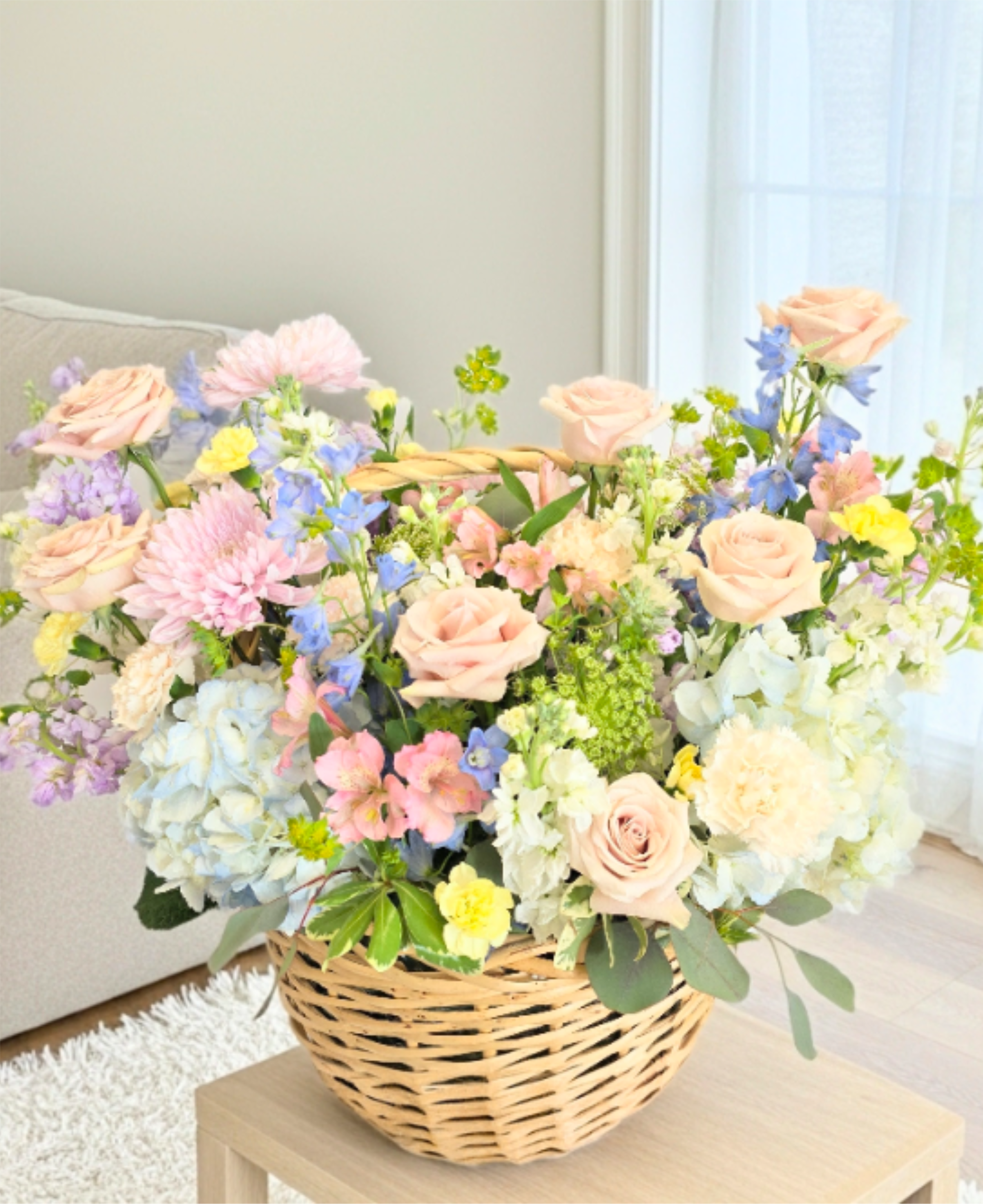 Basket arrangement of pastel roses, hydrangeas, and mixed blooms