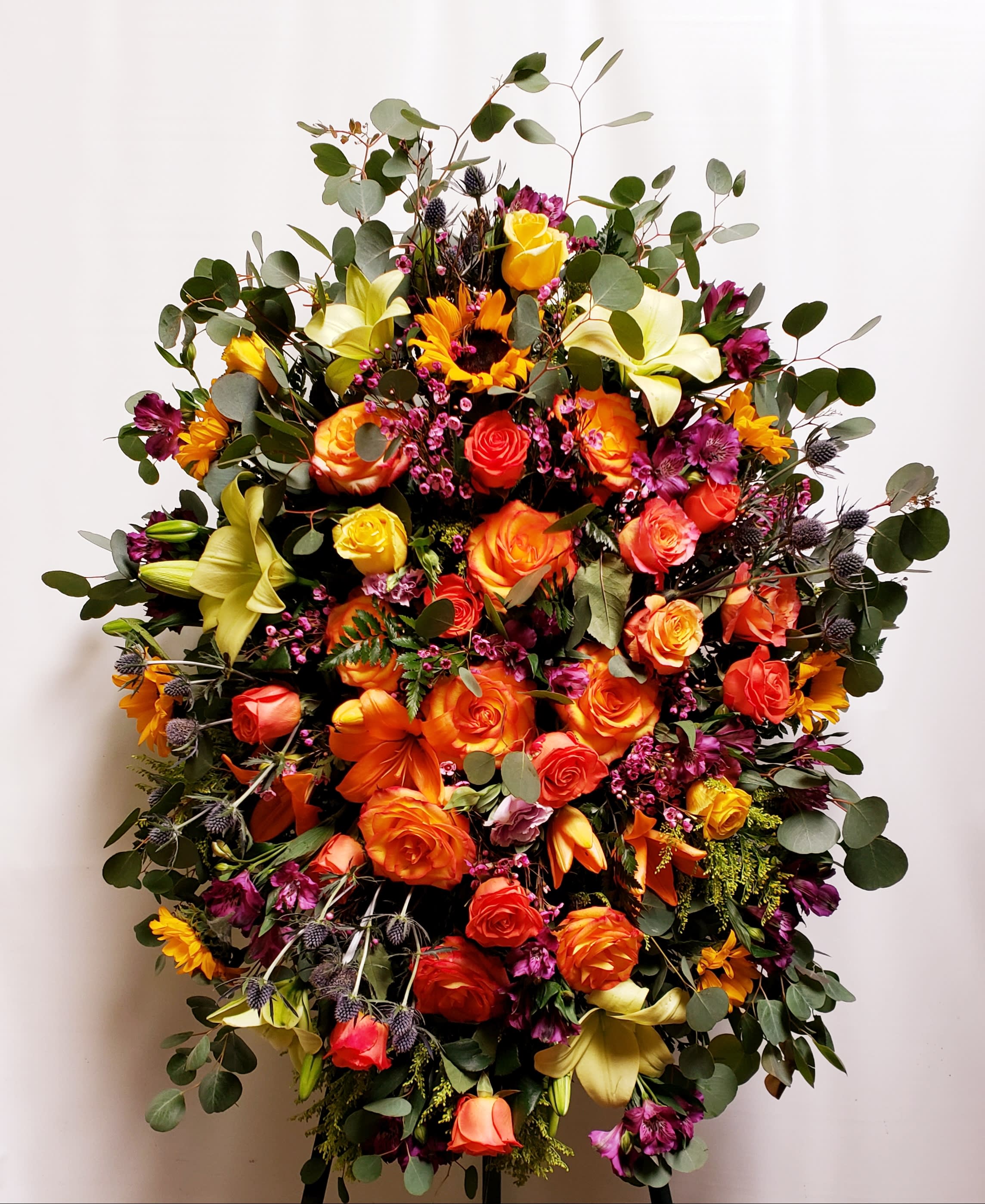 Large bouquet of orange and yellow roses with lilies and greenery