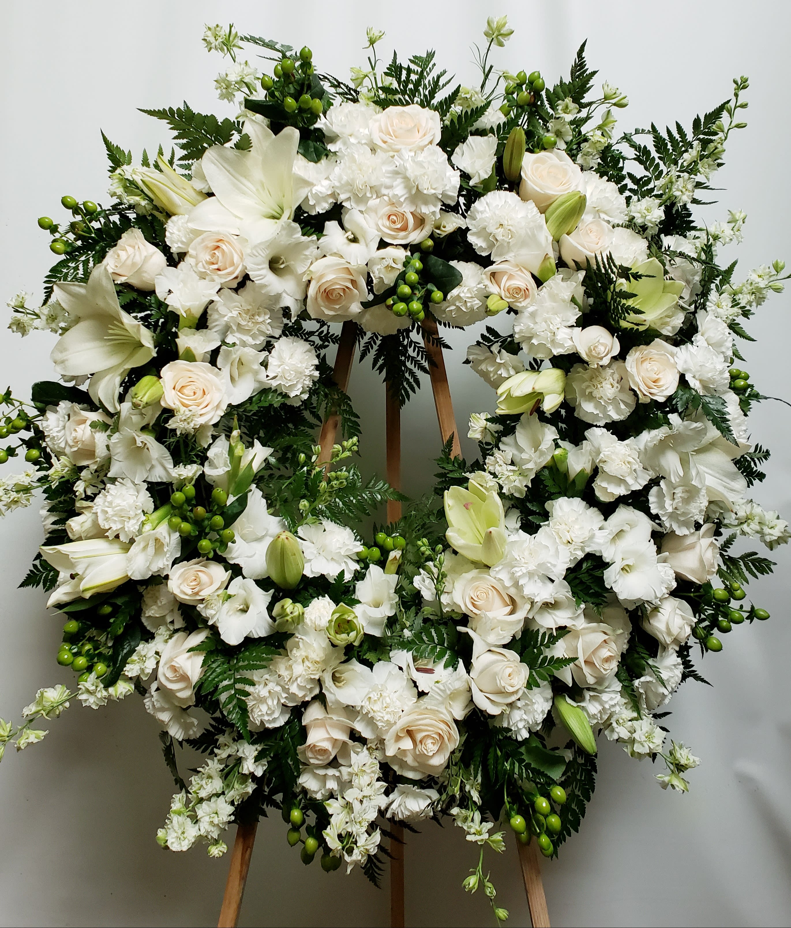 Large white floral wreath on a wooden stand