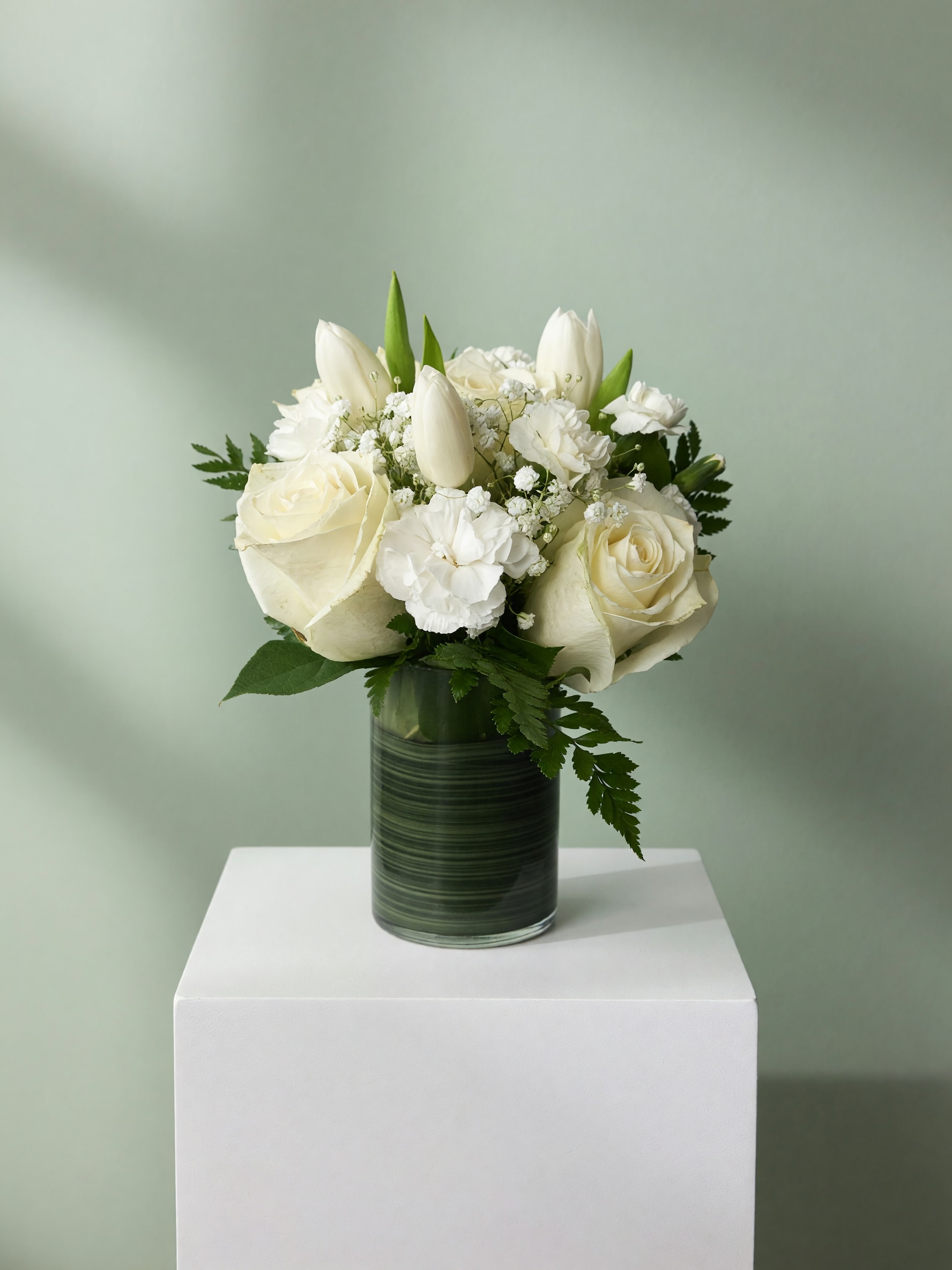 White roses and tulips arranged in a glass vase