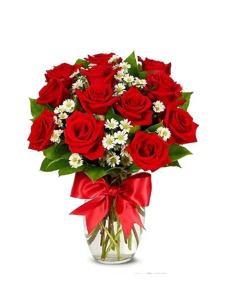Bouquet of red roses and white daisies in a clear glass vase with a red ribbon
