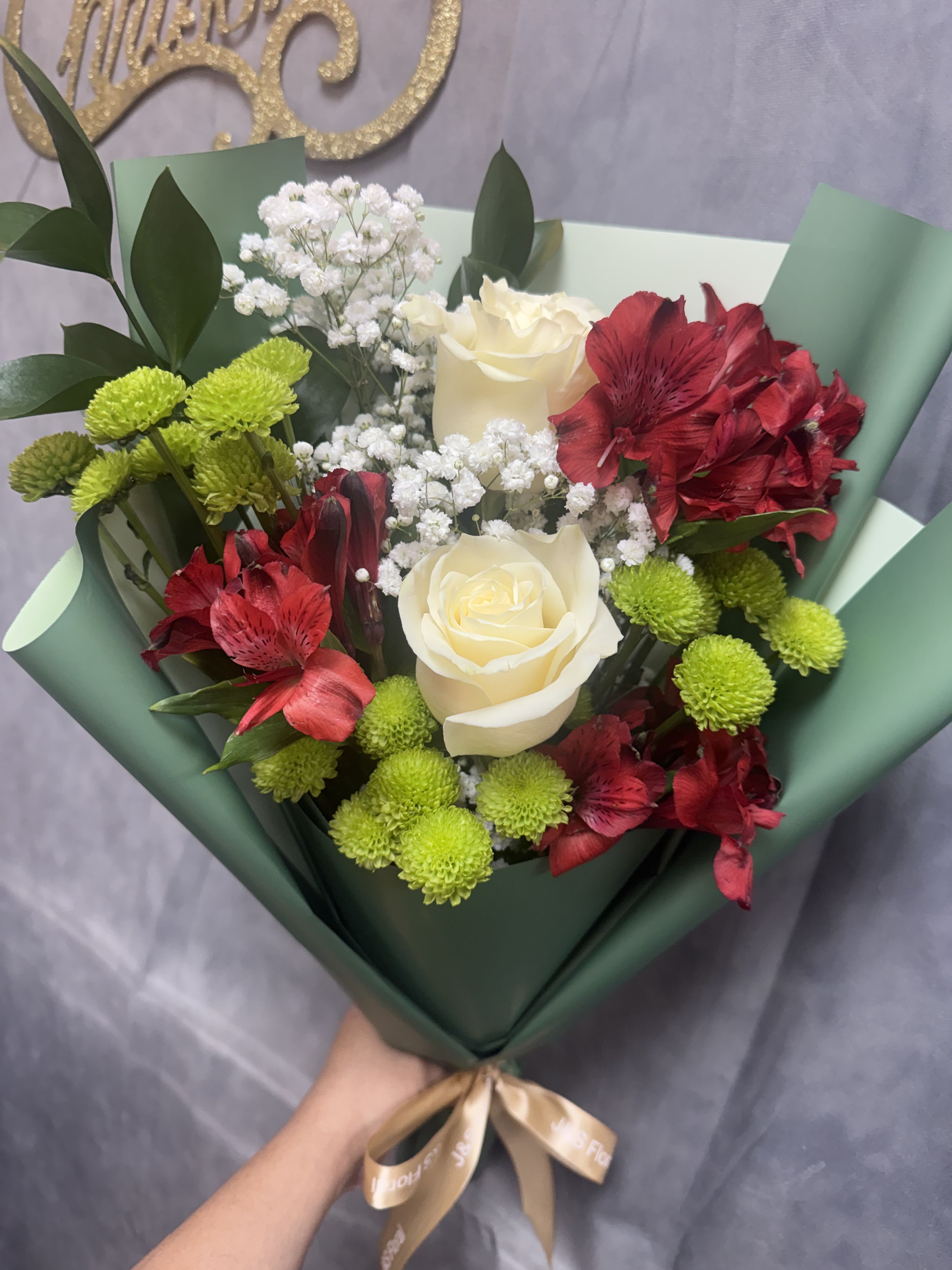 Holiday Harmony Bouquet  - A festive blend of classic elegance and seasonal cheer, featuring rich red blooms, creamy white roses, fresh evergreen accents, and delicate baby’s breath. Perfect for spreading warmth, joy, and holiday magic to someone special. 