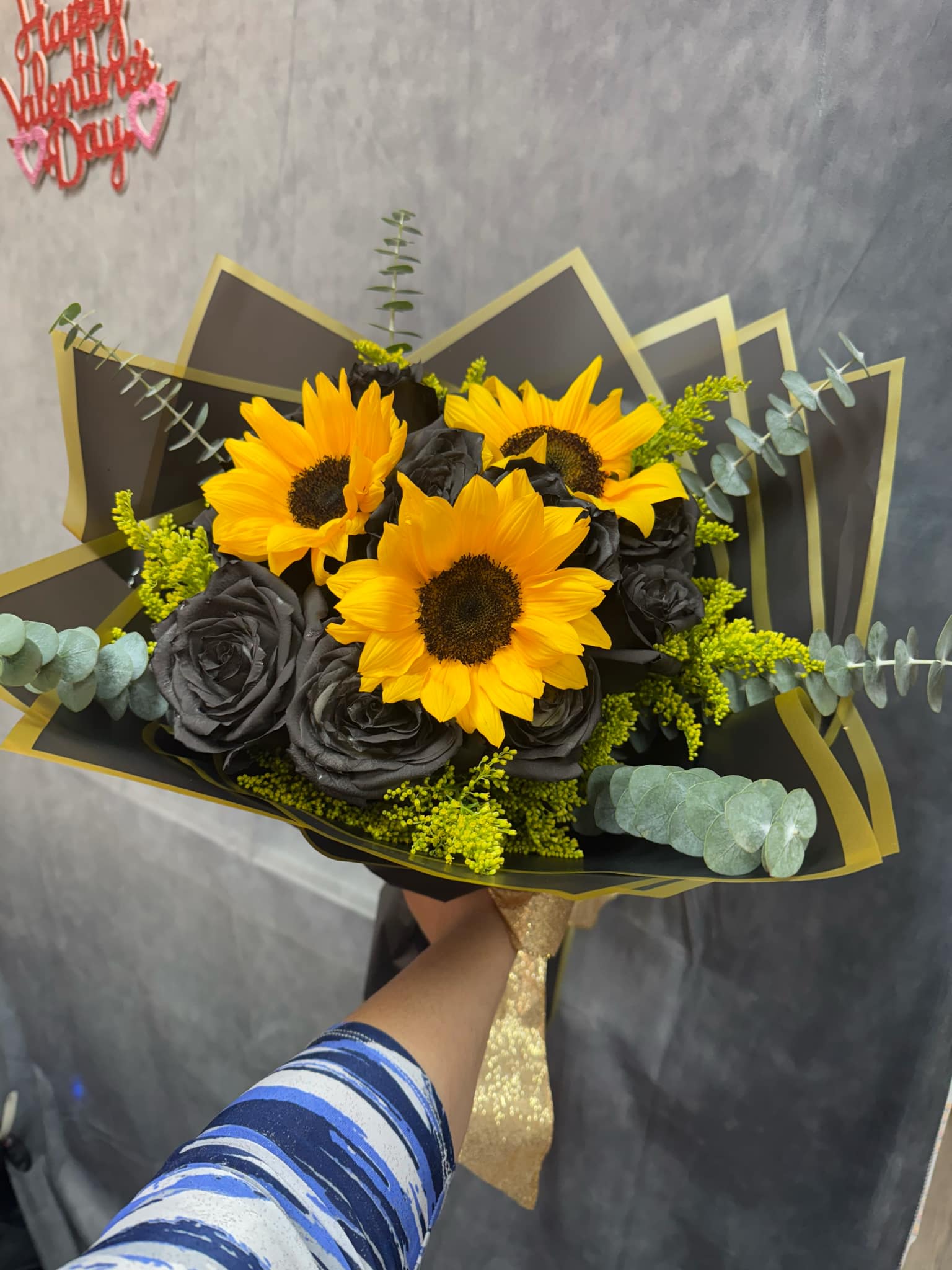 Bouquet of yellow sunflowers and black roses wrapped in black paper