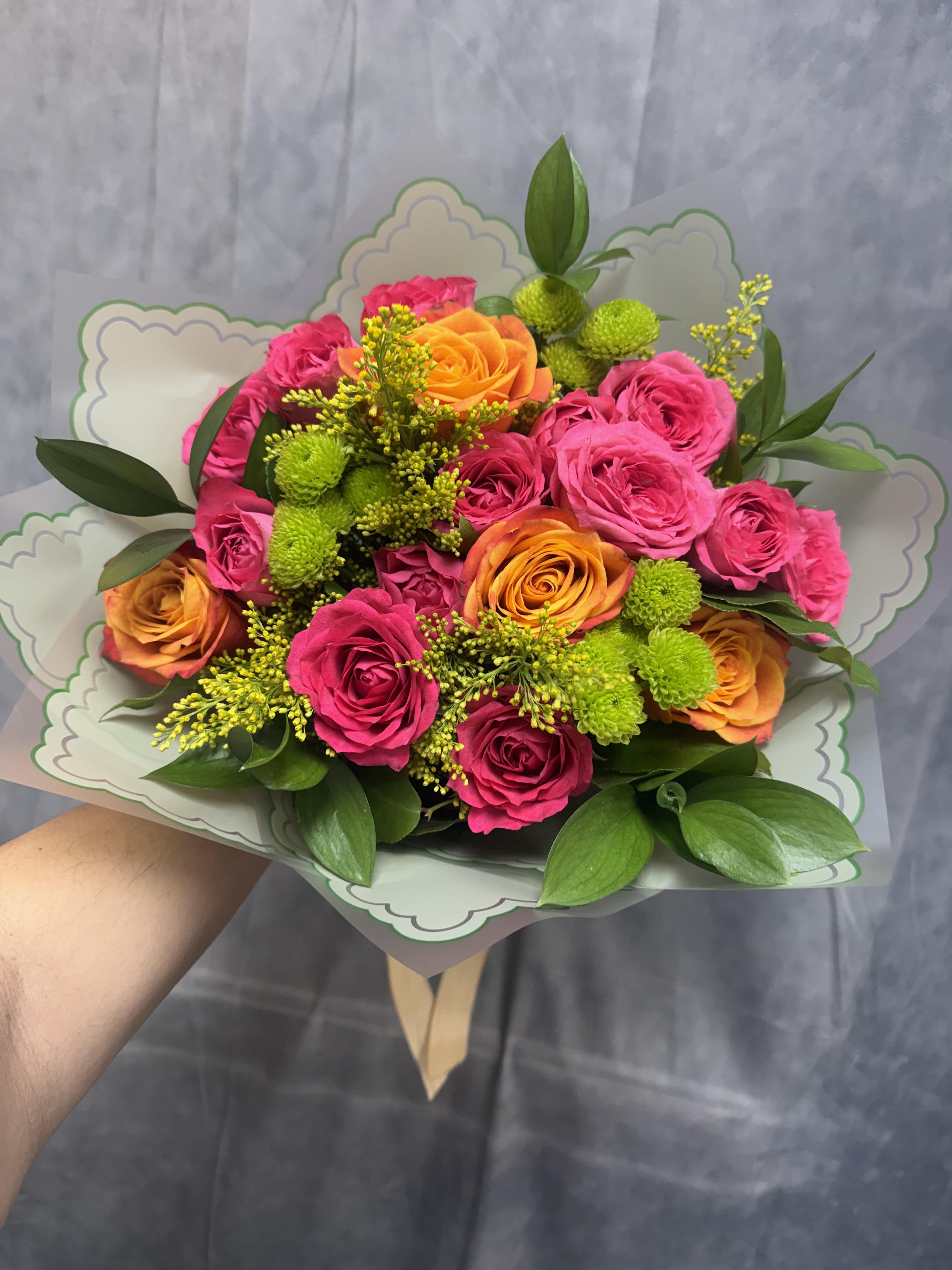 Bold &amp; Sweet Bouquet - A vibrant mix of hot pink and orange roses accented with cheerful green button mums, golden solidago, and fresh greenery. Full of energy, color, and charm, this eye-catching bouquet is the perfect blend of bold beauty and sweet sentiment—ideal for birthdays, celebrations, or making someone’s day extra special. 