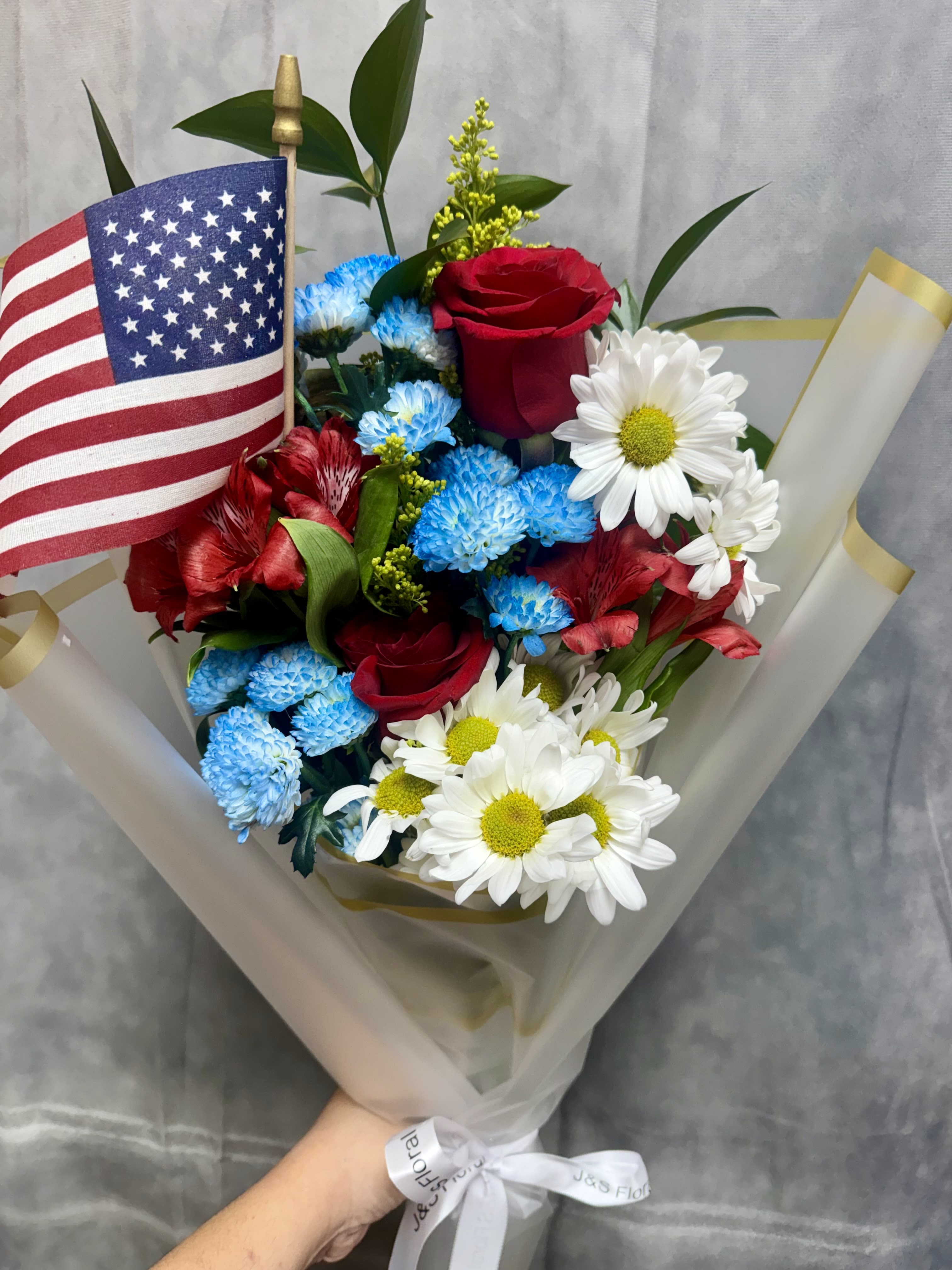 Bouquet of red roses, blue and white daisies, and an American flag