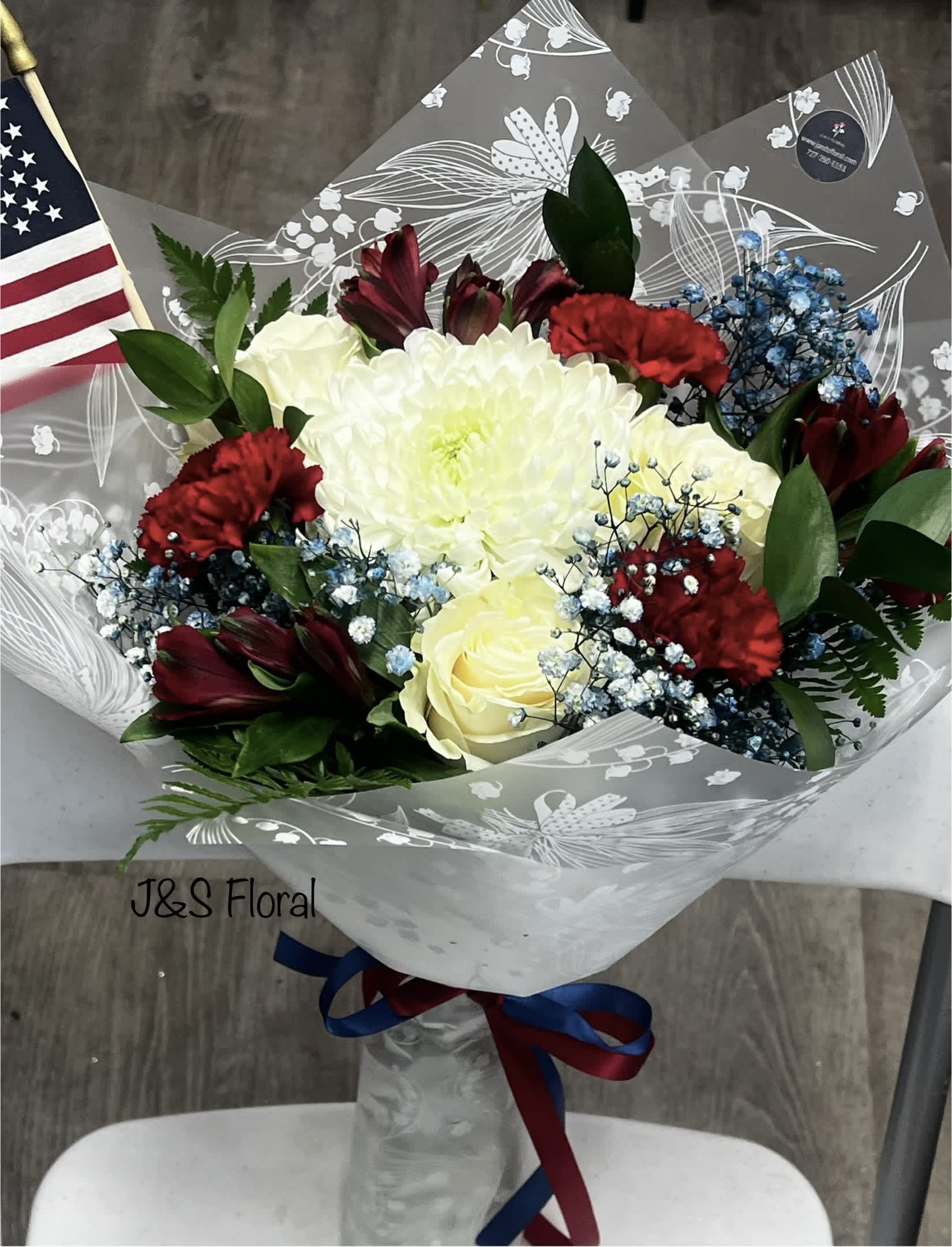 Bouquet of white roses, red carnations, and dark red flowers in clear wrap