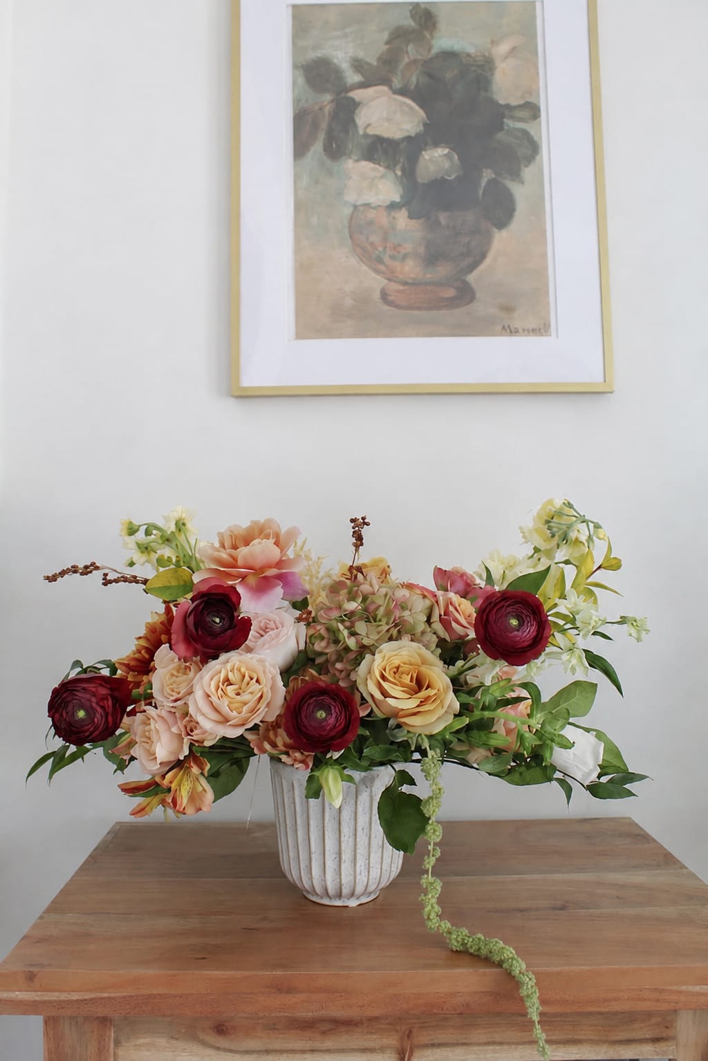 Mixed floral arrangement in a white vase on a wooden table