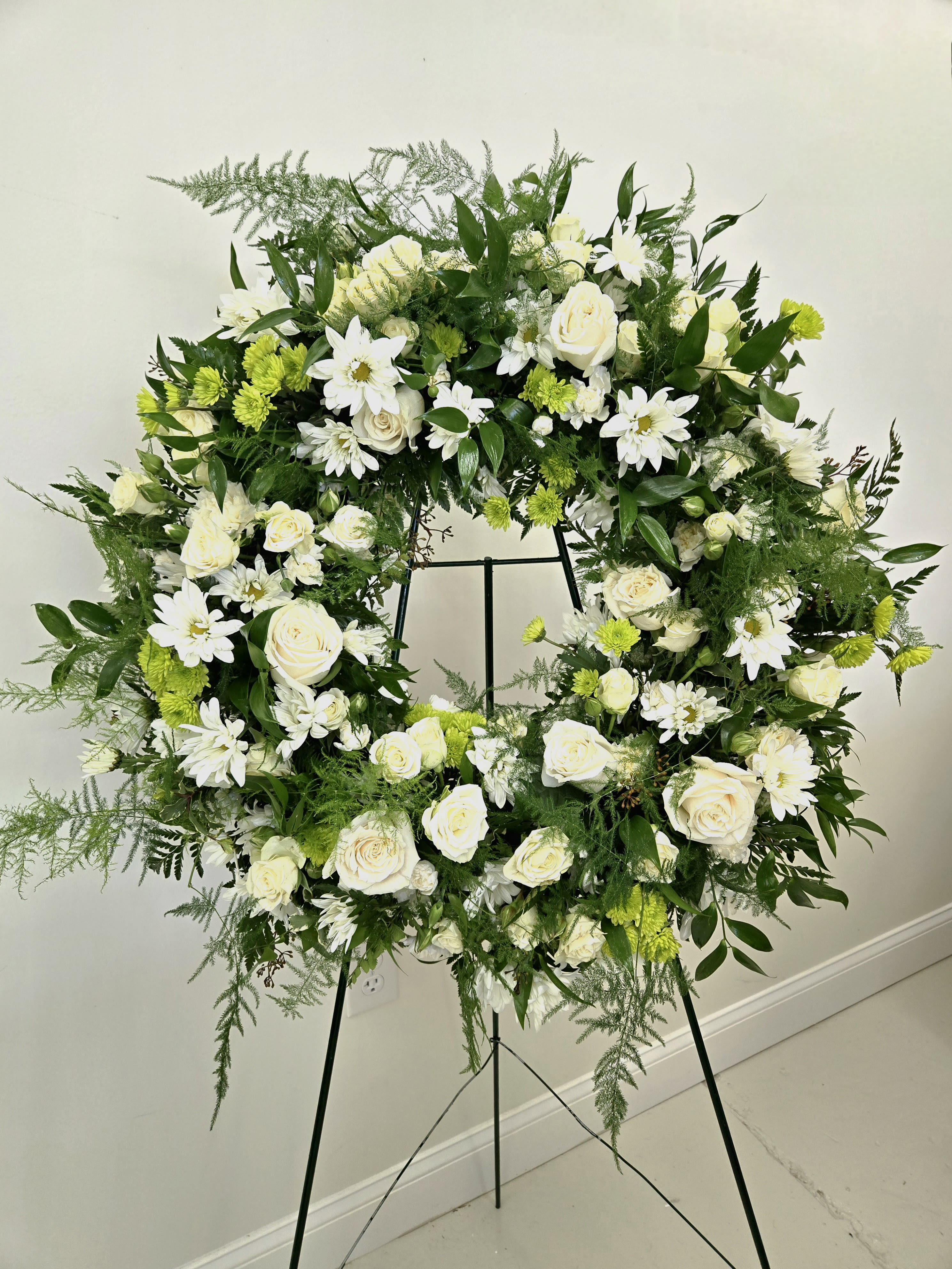 Large white and green floral wreath on a stand
