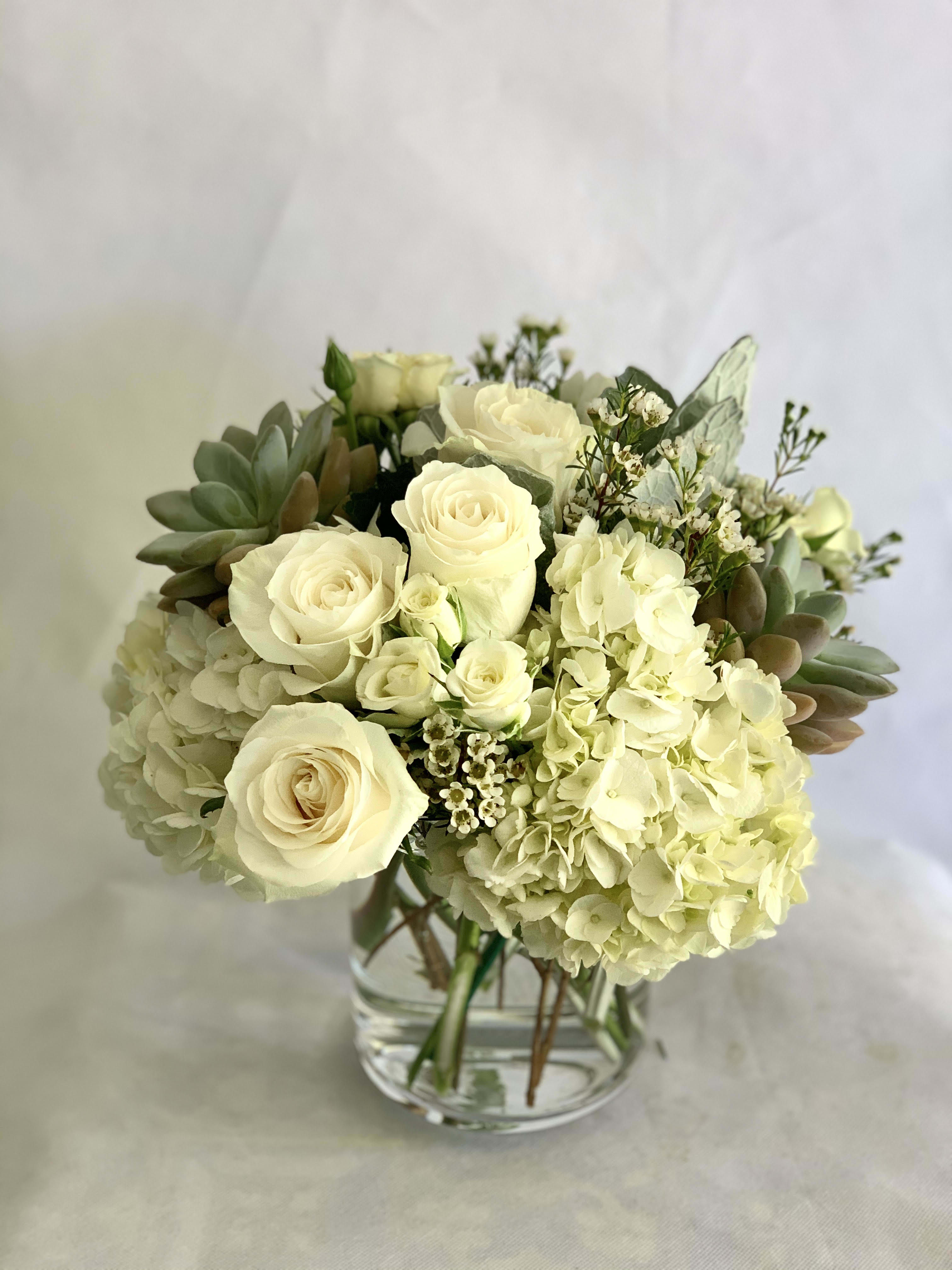 Cream roses and hydrangeas arranged in a clear glass vase