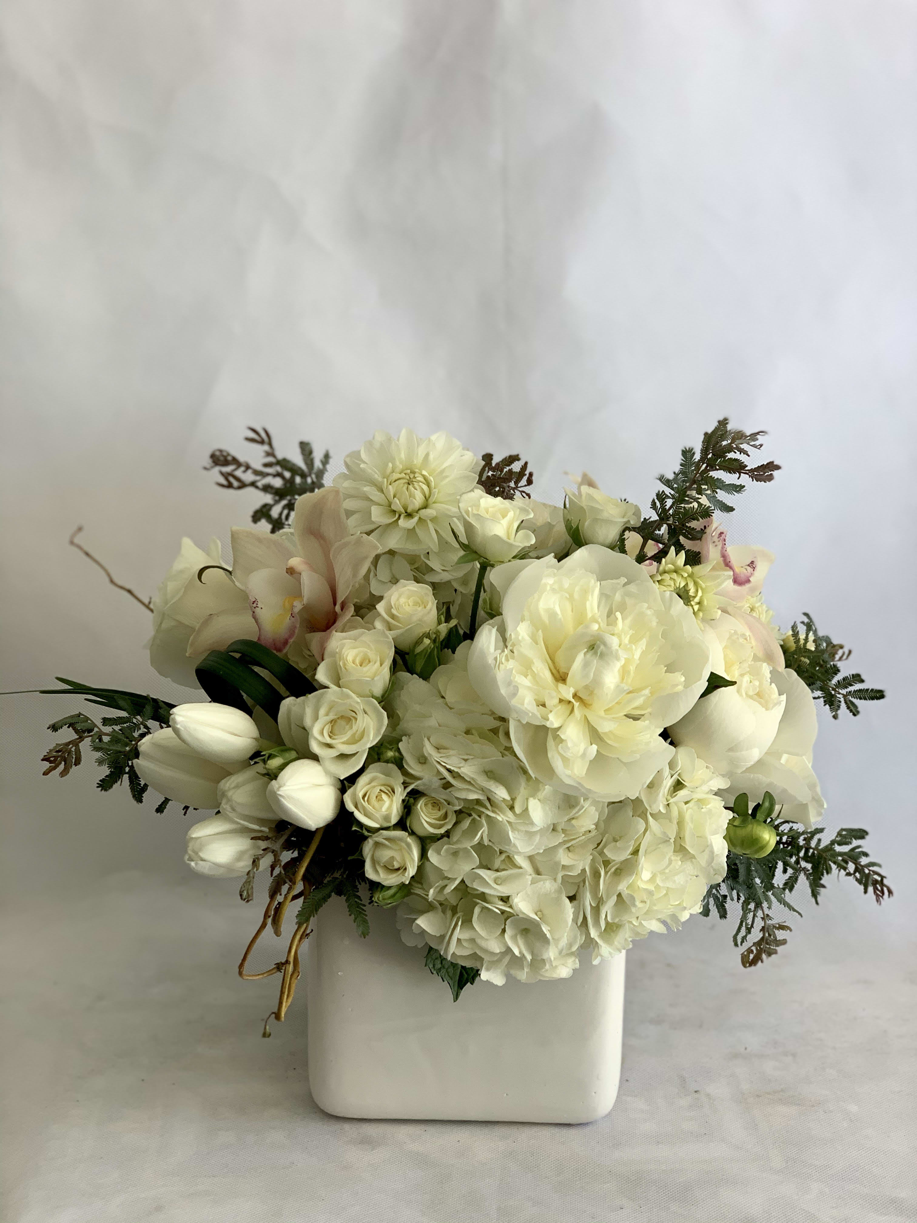 White floral arrangement in a square ceramic vase