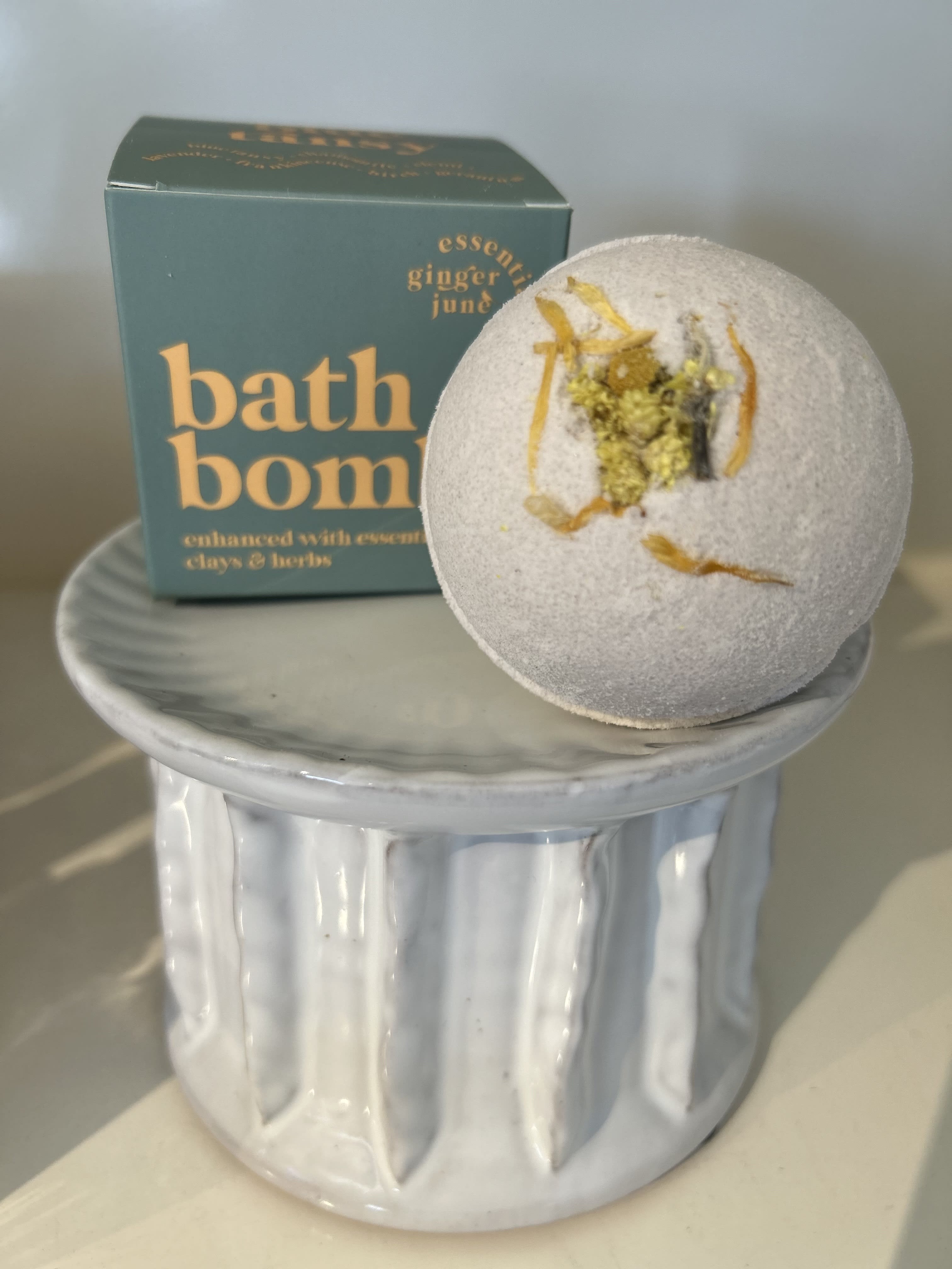Bath bomb on a ceramic pedestal with its box behind it