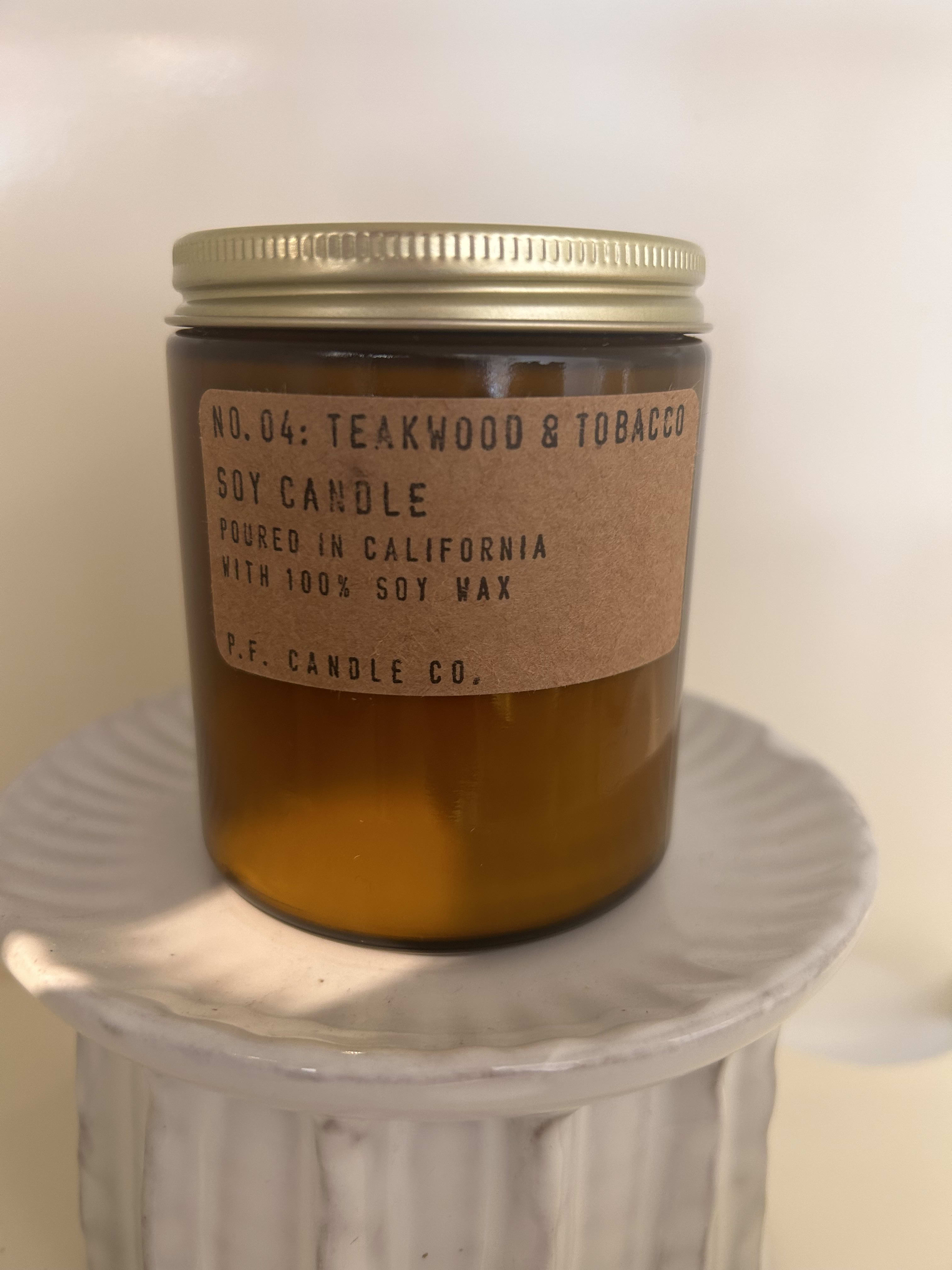 Amber jar candle with a gold lid on a white pedestal