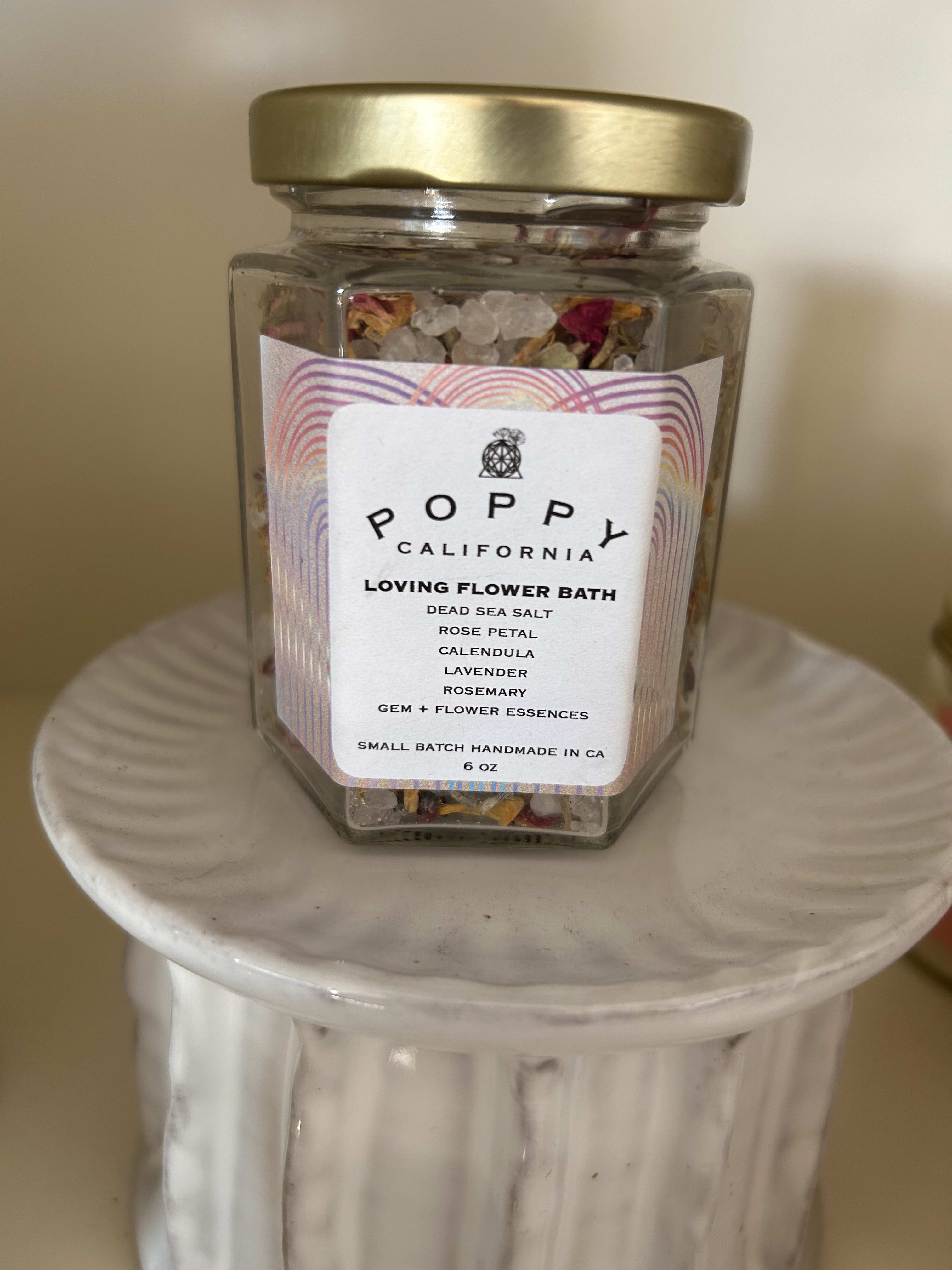 Jar of flower bath salts with a gold lid on a white pedestal