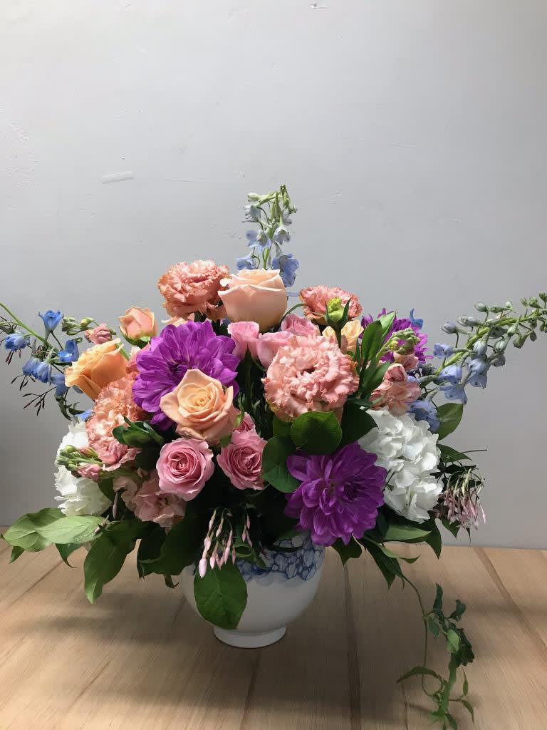 Mixed pink, purple, and blue flowers in a white vase
