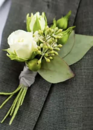 White boutonniere with green buds and leaves on a suit jacket