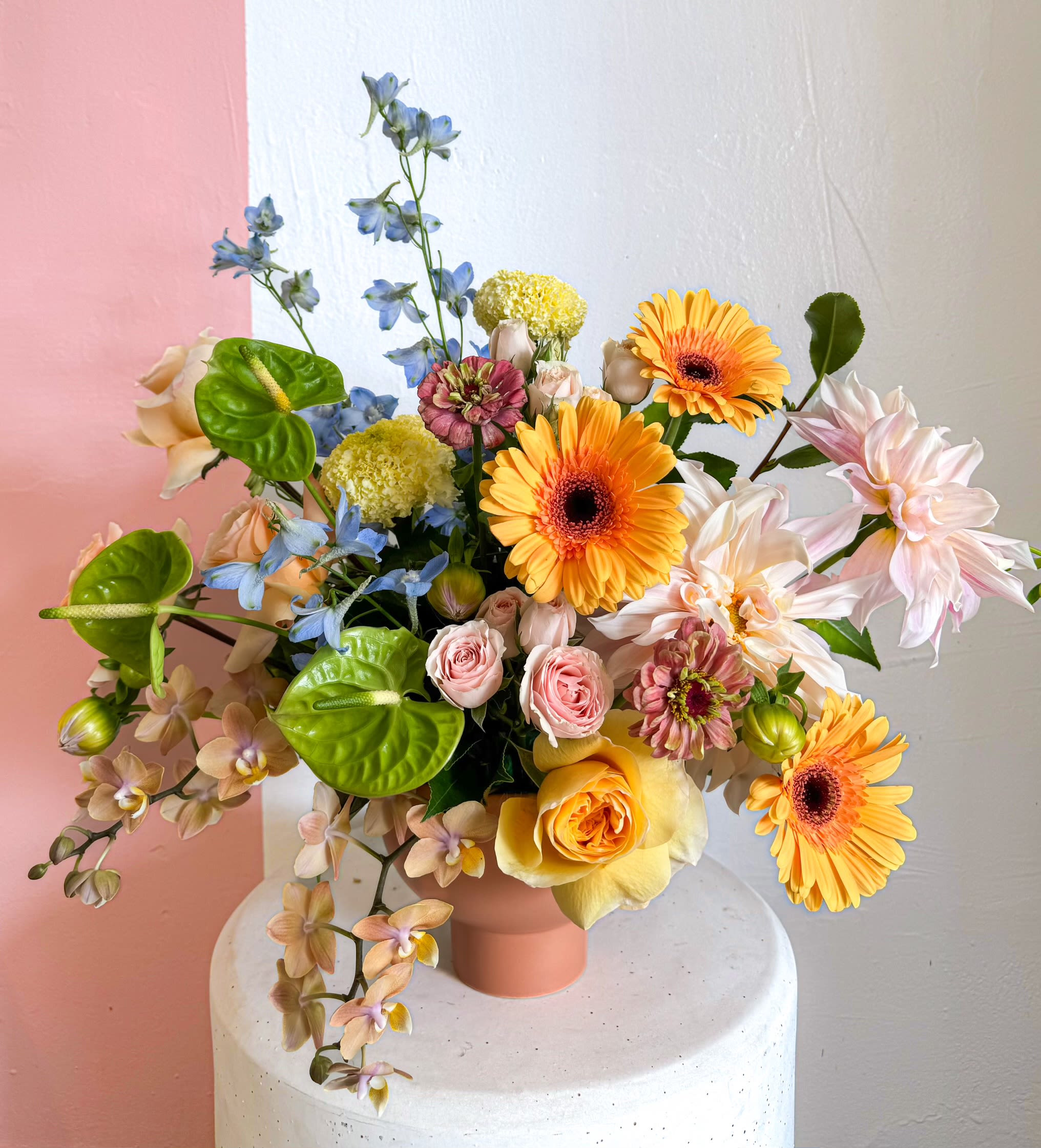 Mixed bouquet in a pink vase with orange, pink, blue, and white flowers