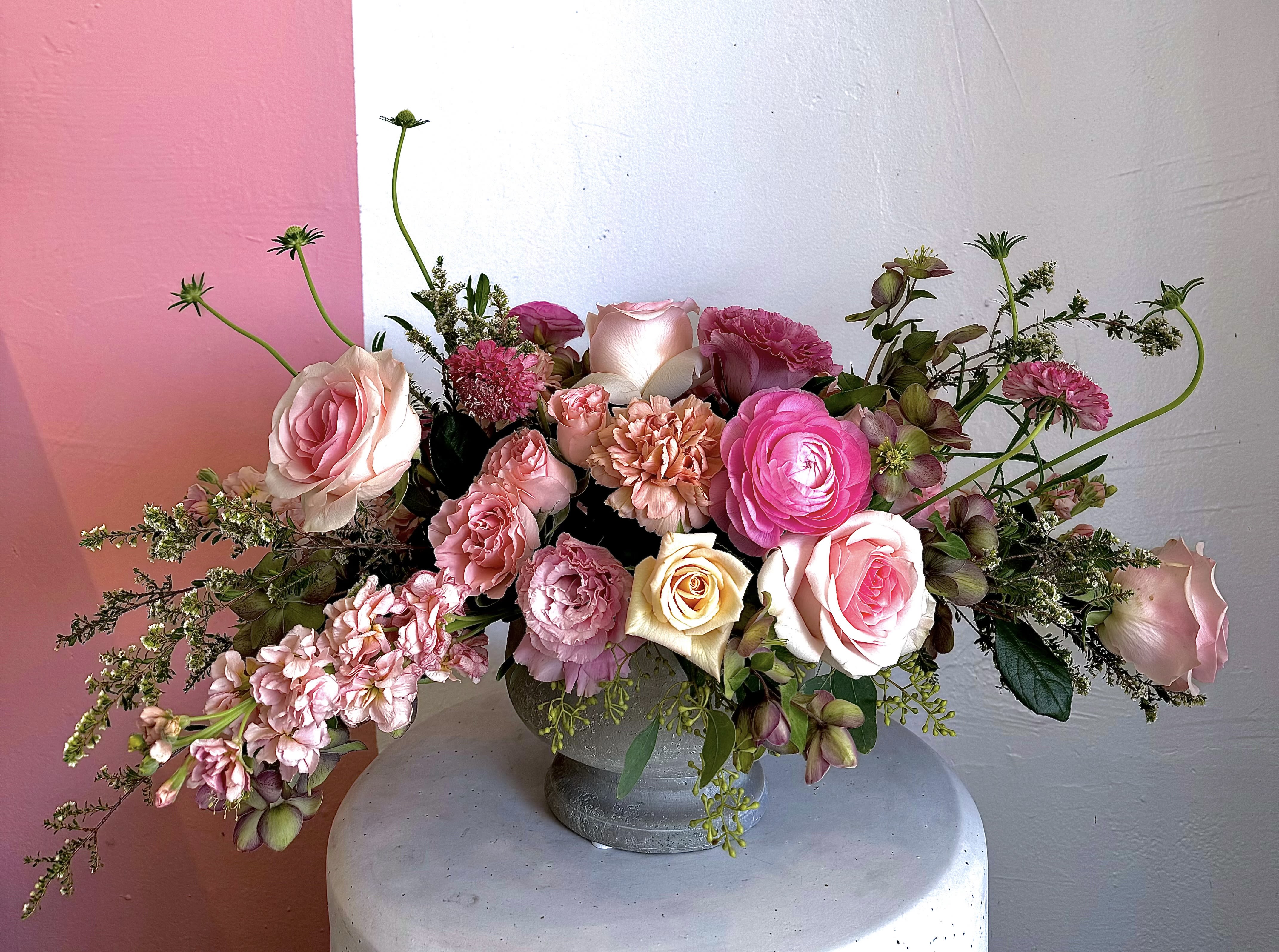 Pink and cream rose arrangement in a gray vase