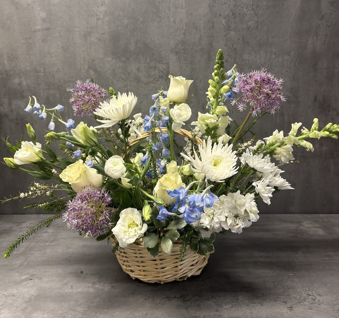 Basket arrangement of white and blue flowers with purple allium