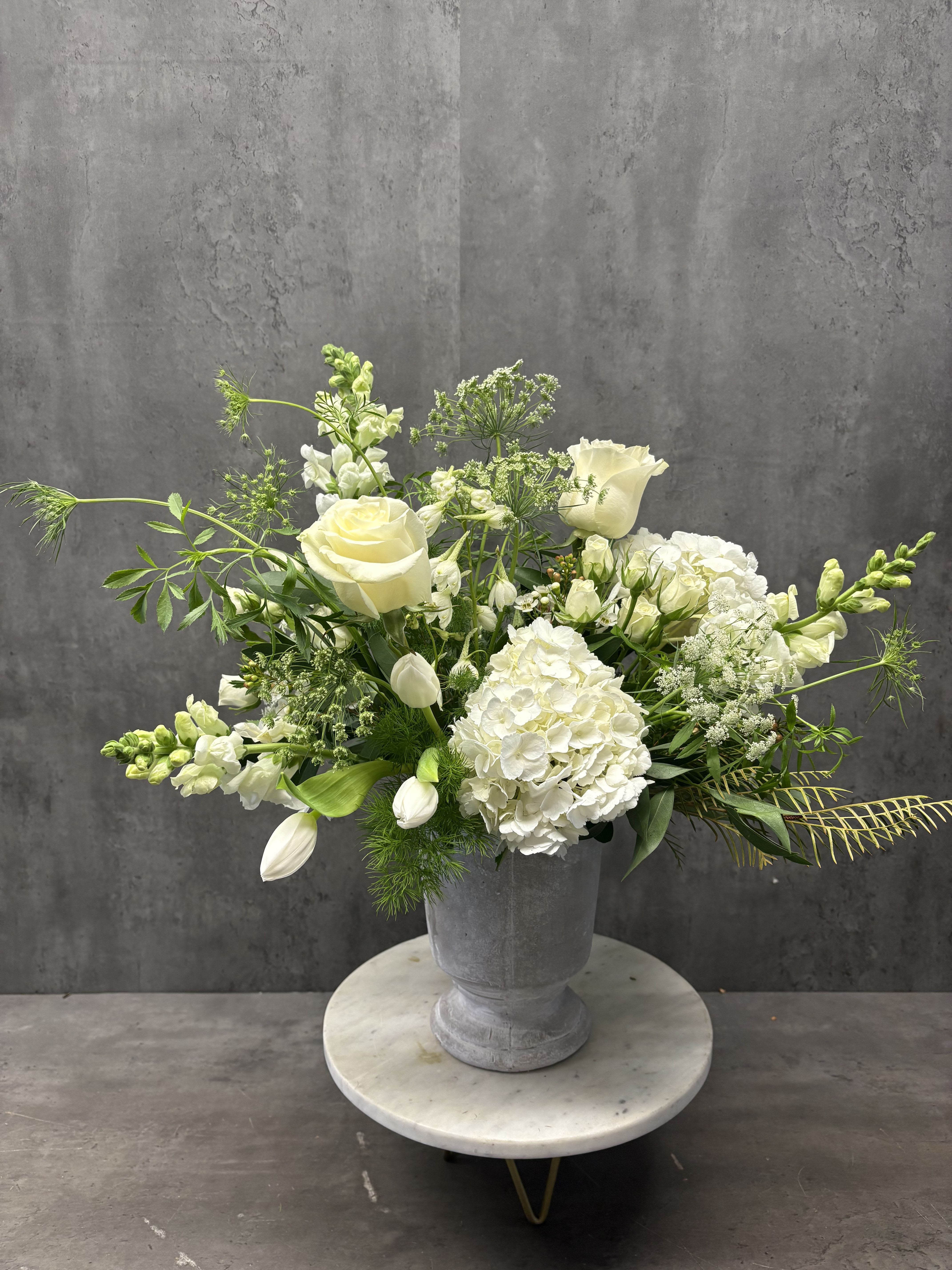 White roses and hydrangeas arranged in a gray urn