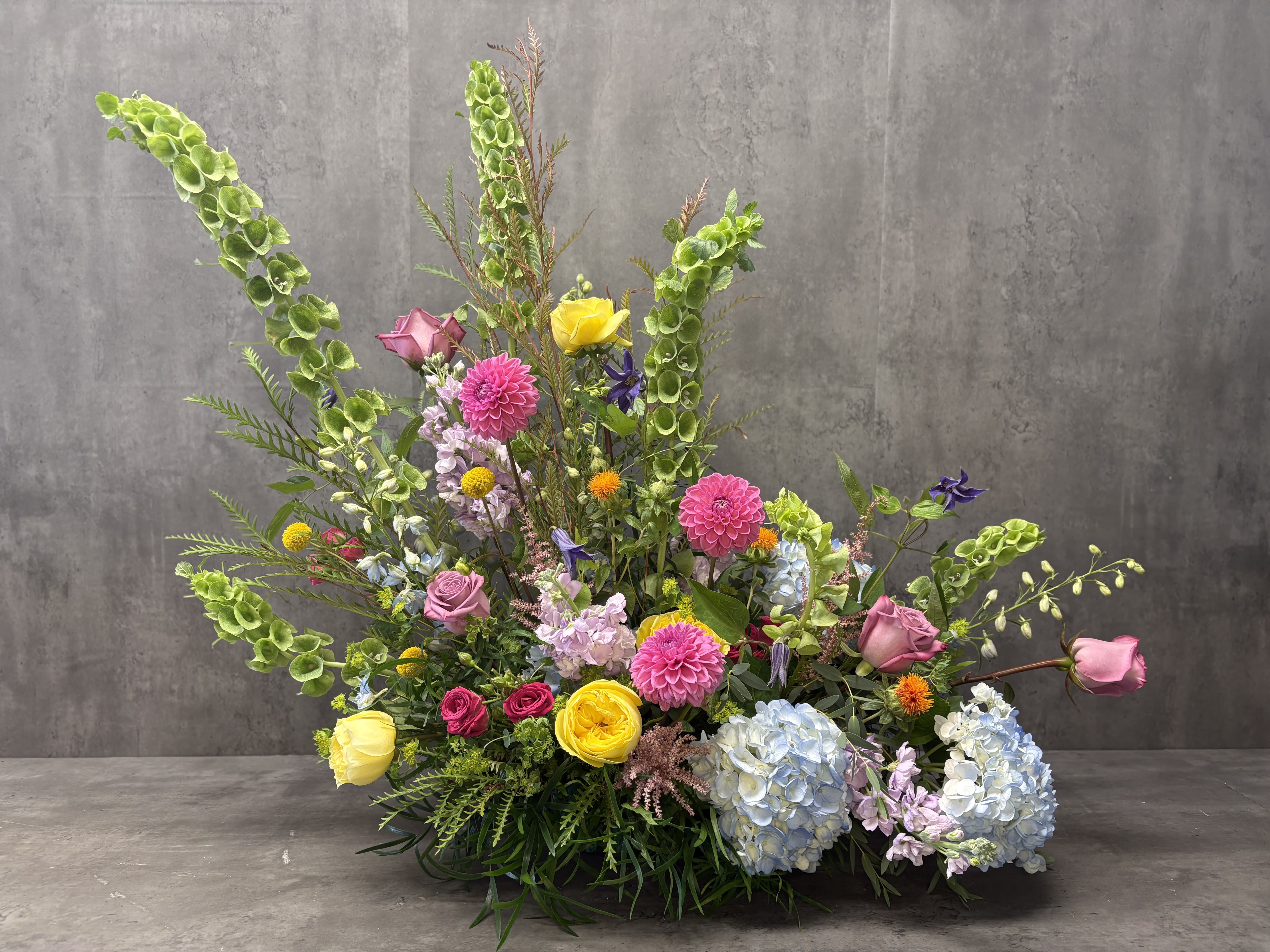 Large mixed floral arrangement with pink, yellow, blue, and green blooms