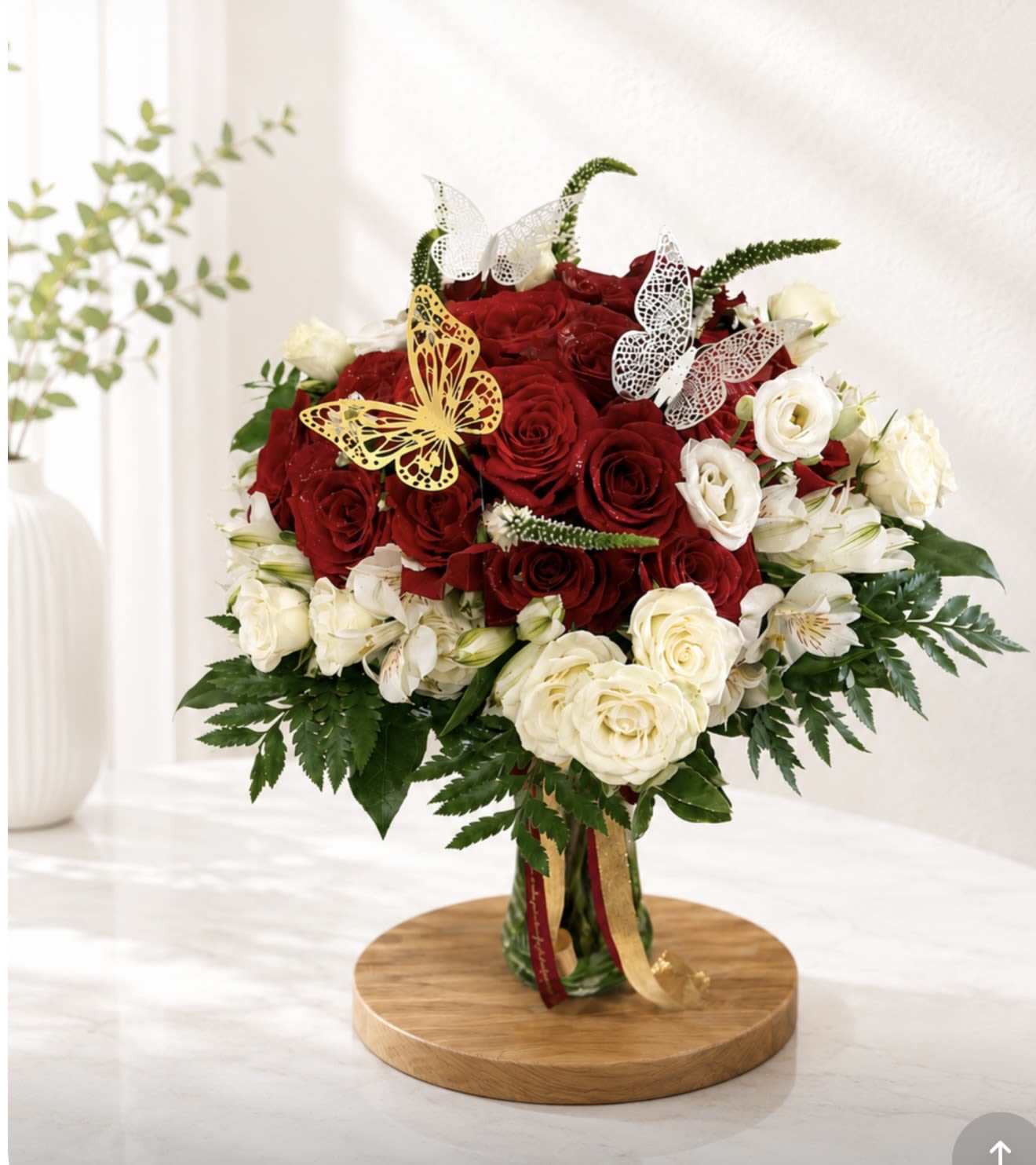 Love Takes Flight - A stunning arrangement of luxurious red and white roses accented with delicate white blooms, lush greenery, and elegant decorative butterflies. The rich red roses symbolize love and admiration, while the soft white flowers add grace, beauty, and sophistication. Perfect for birthdays, anniversaries, celebrations, sympathy gestures, or any occasion where you want to make a lasting impression.