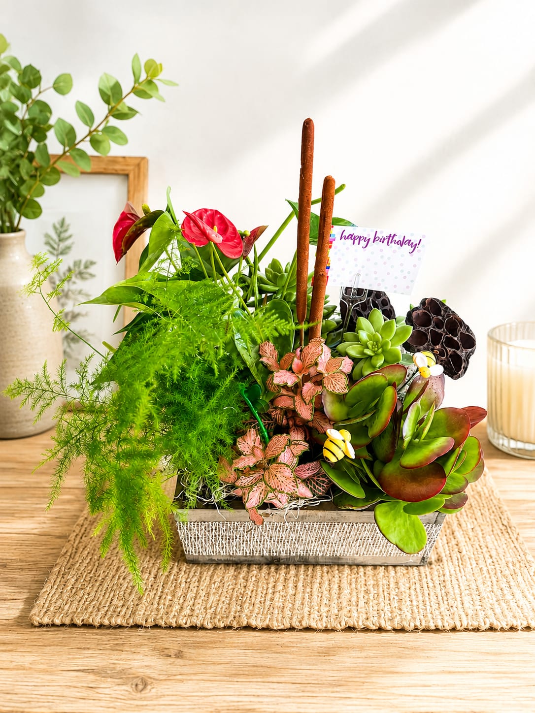 Tropical Serenity Garden - Bring nature indoors with this lush and vibrant garden planter featuring a beautiful mix of premium tropical foliage, colorful fittonia, elegant red anthuriums, sculptural succulents, and natural accents. Designed in a rustic container, this long-lasting arrangement adds texture, color, and a refreshing touch of greenery to any home or office.  Perfect for birthdays, celebrations, thank-you gifts, housewarmings, or simply brightening someone's day. Due to seasonal availability, plant varieties and decorative accents may vary while maintaining the overall style, beauty, and value of the arrangement.
